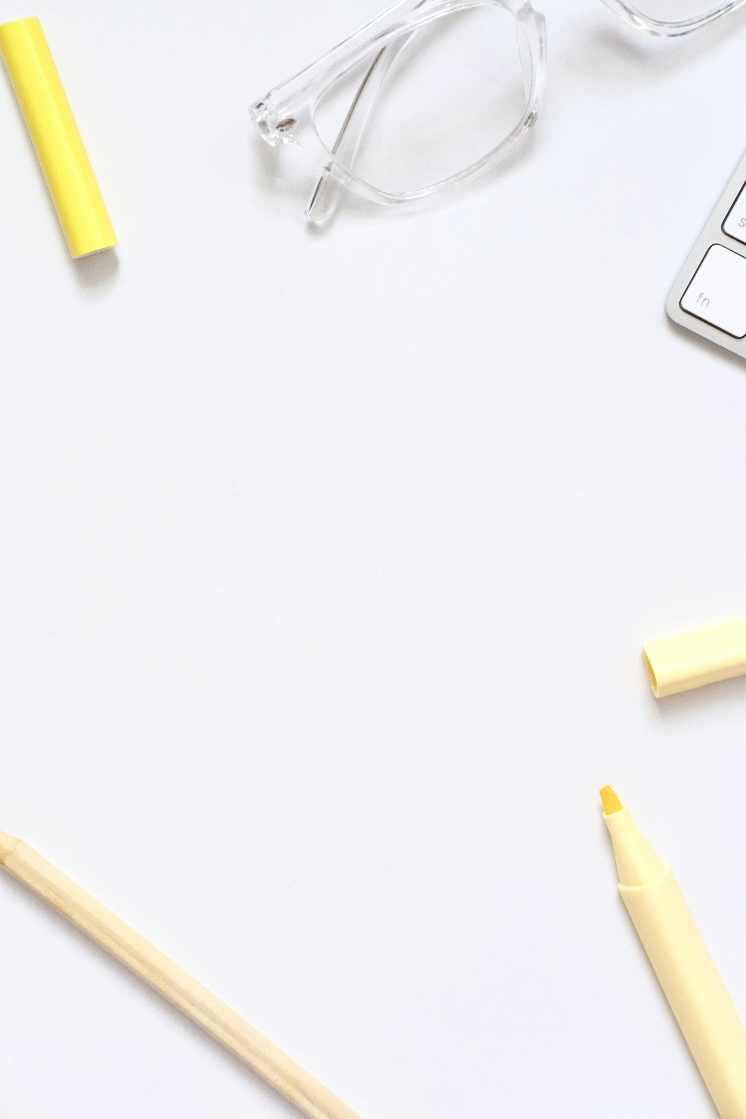 Desk essentials: glasses, keyboard, pencil, and markers.