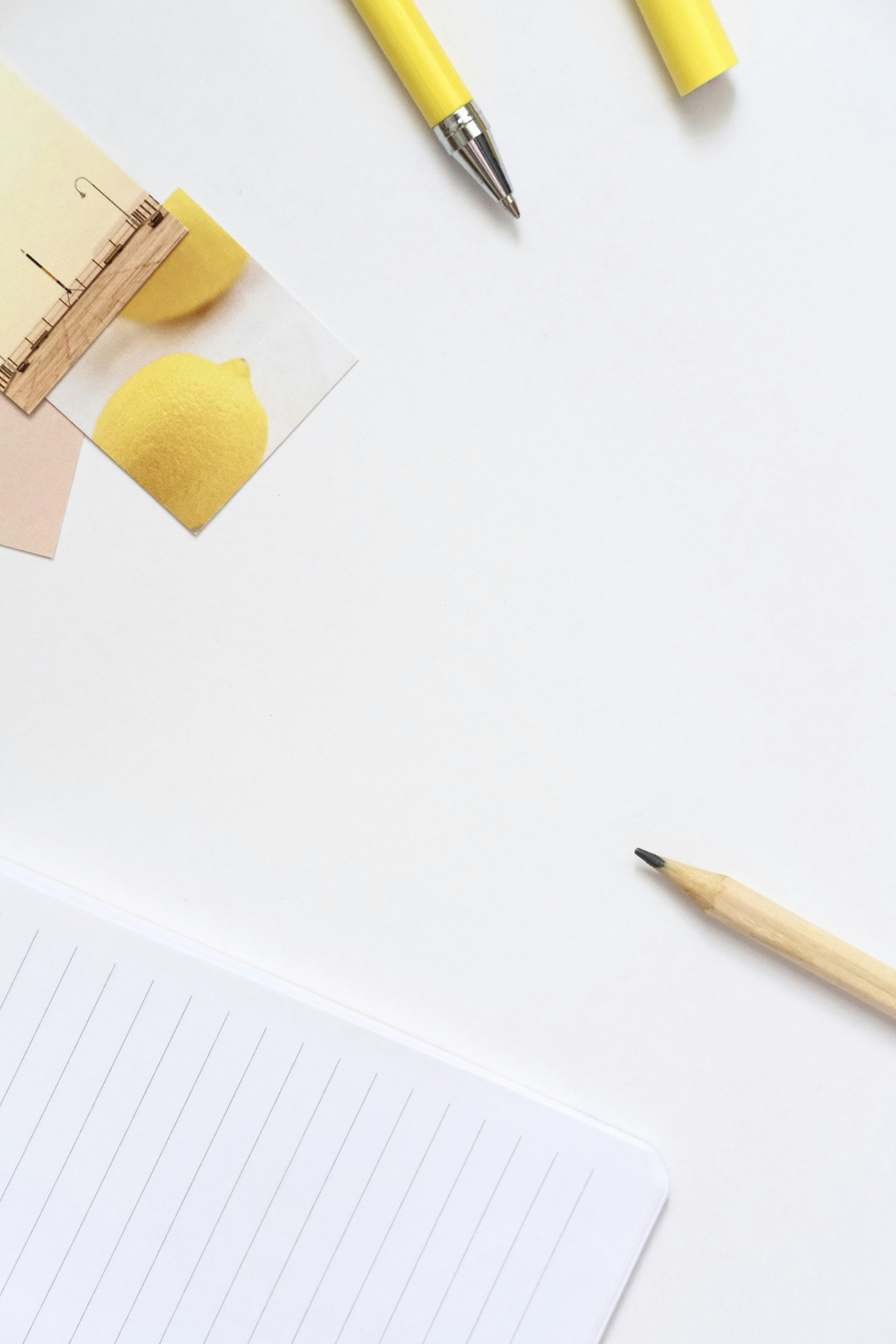Yellow pens and a lemon on a white surface.