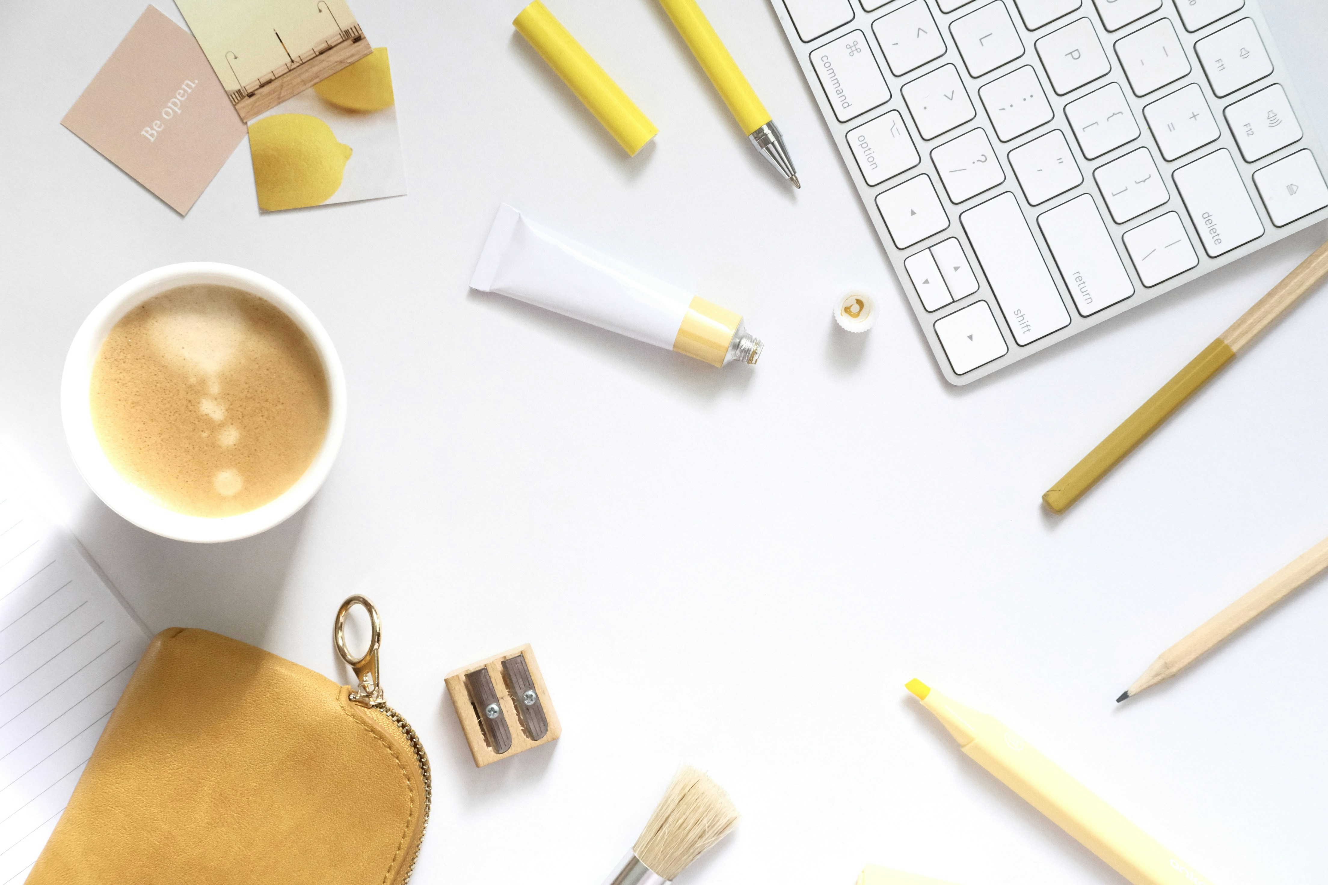 Flat lay of a desk with coffee and art supplies.