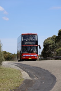 Red double-decker bus driving on a winding road.