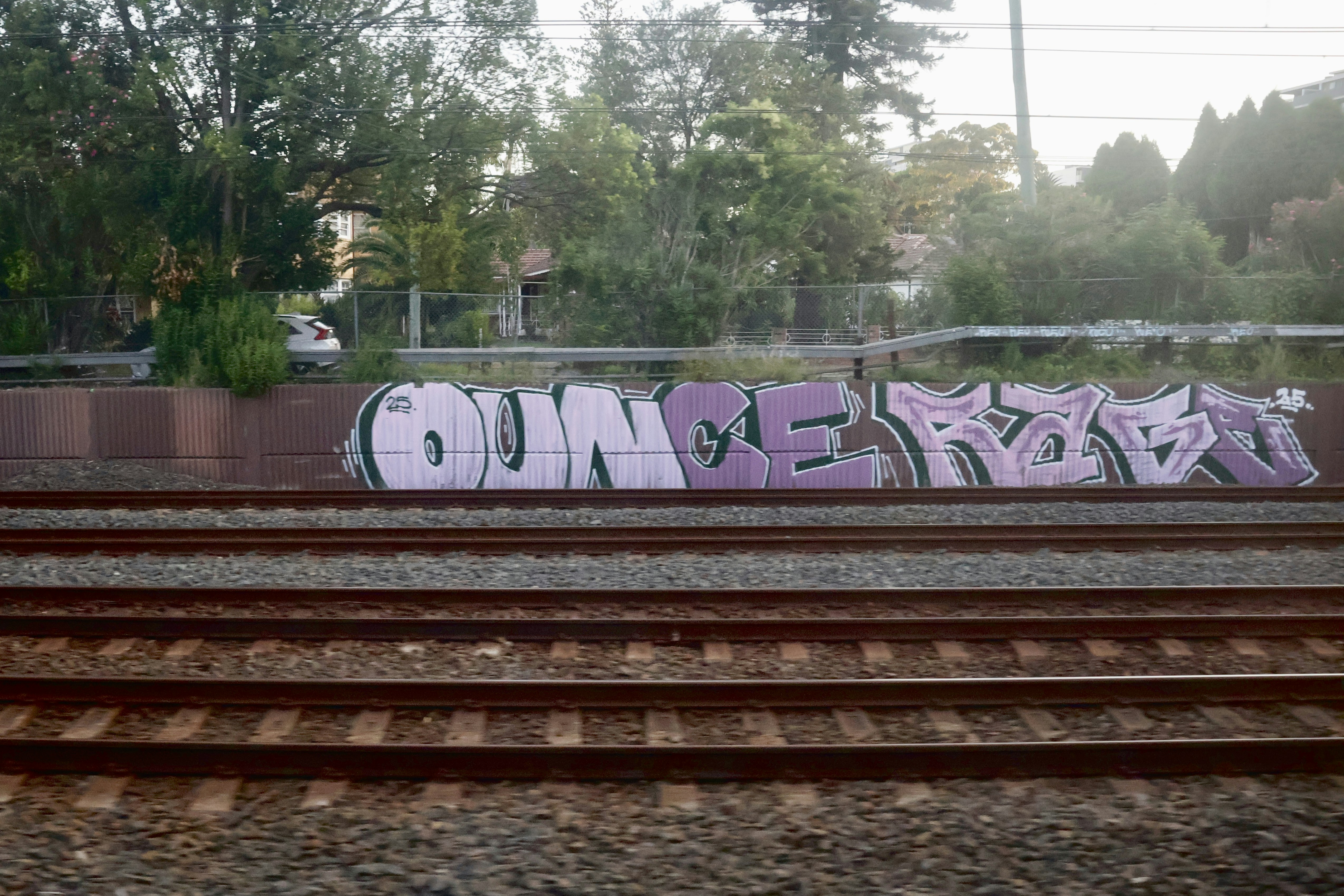 Graffiti art on a retaining wall by train tracks.