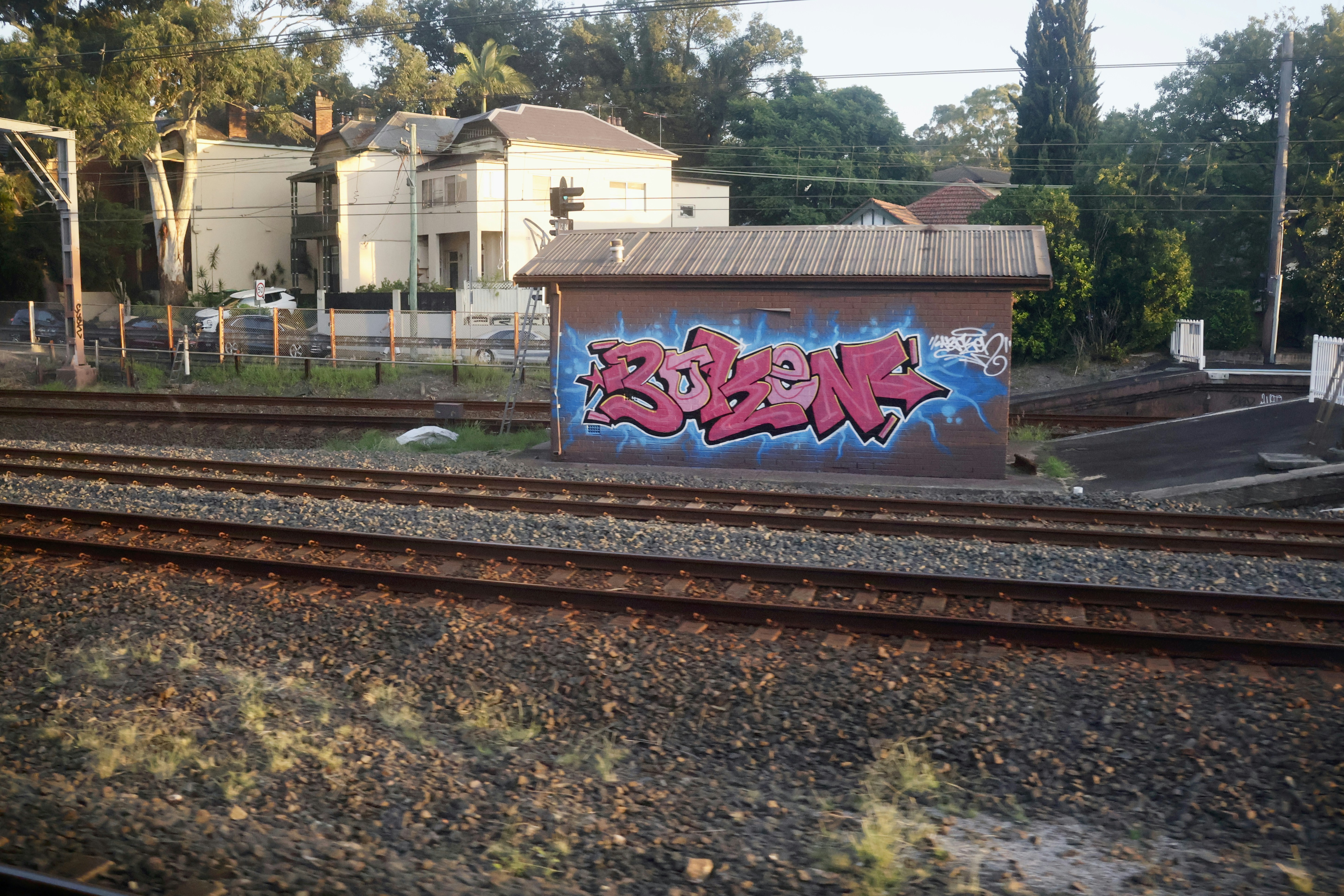 Graffiti on a small building near train tracks.
