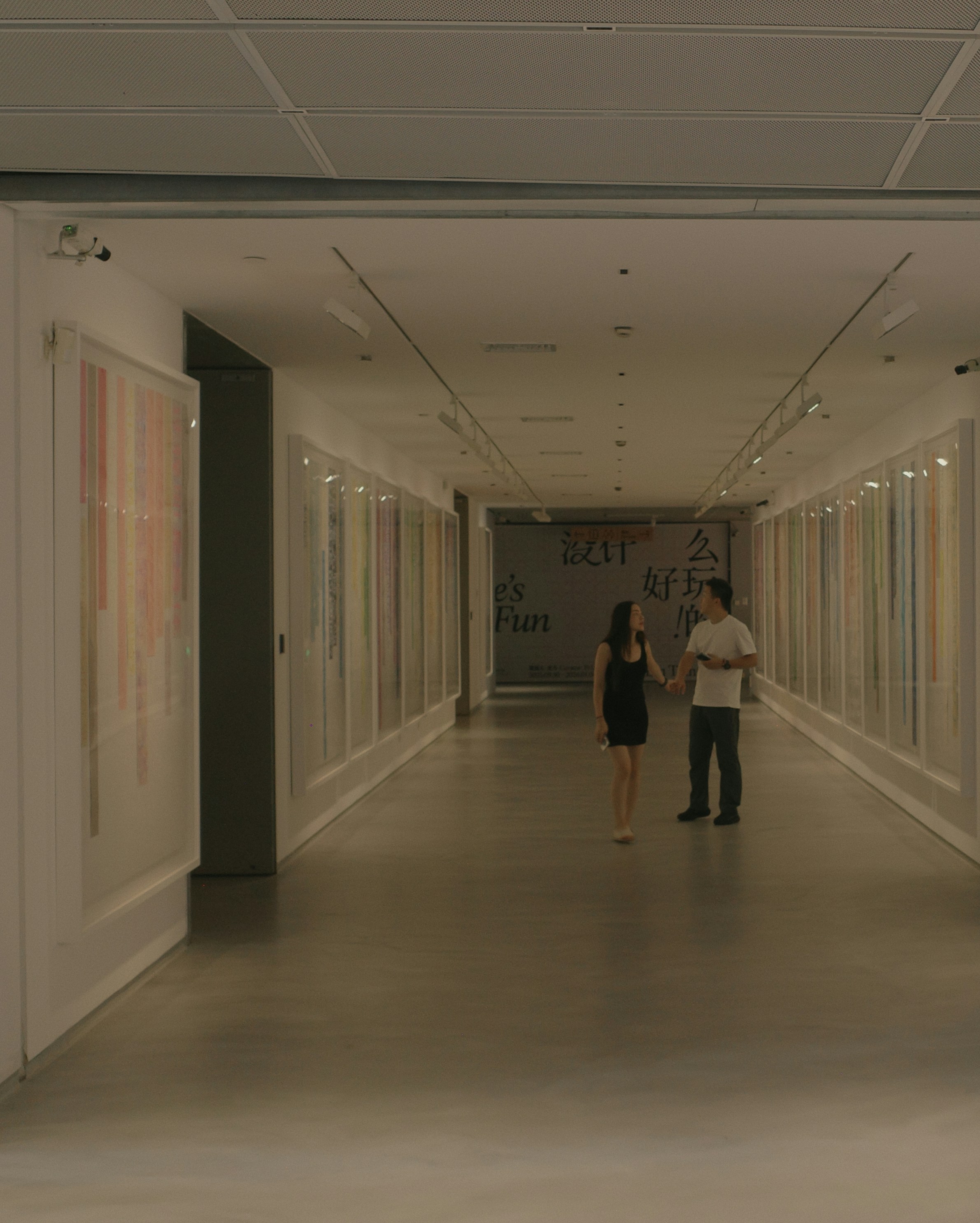 Couple walking through a brightly lit art gallery hallway