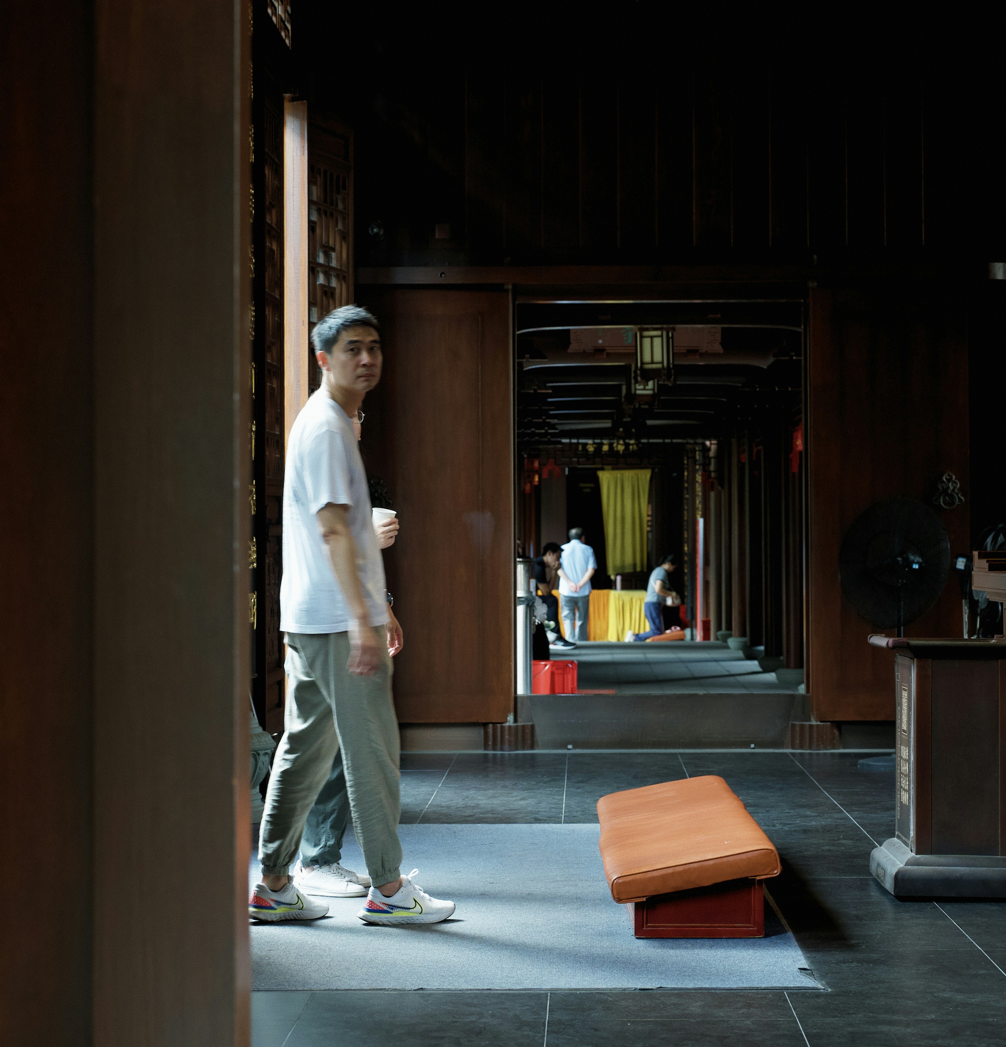 Man in white shirt walks through temple doorway