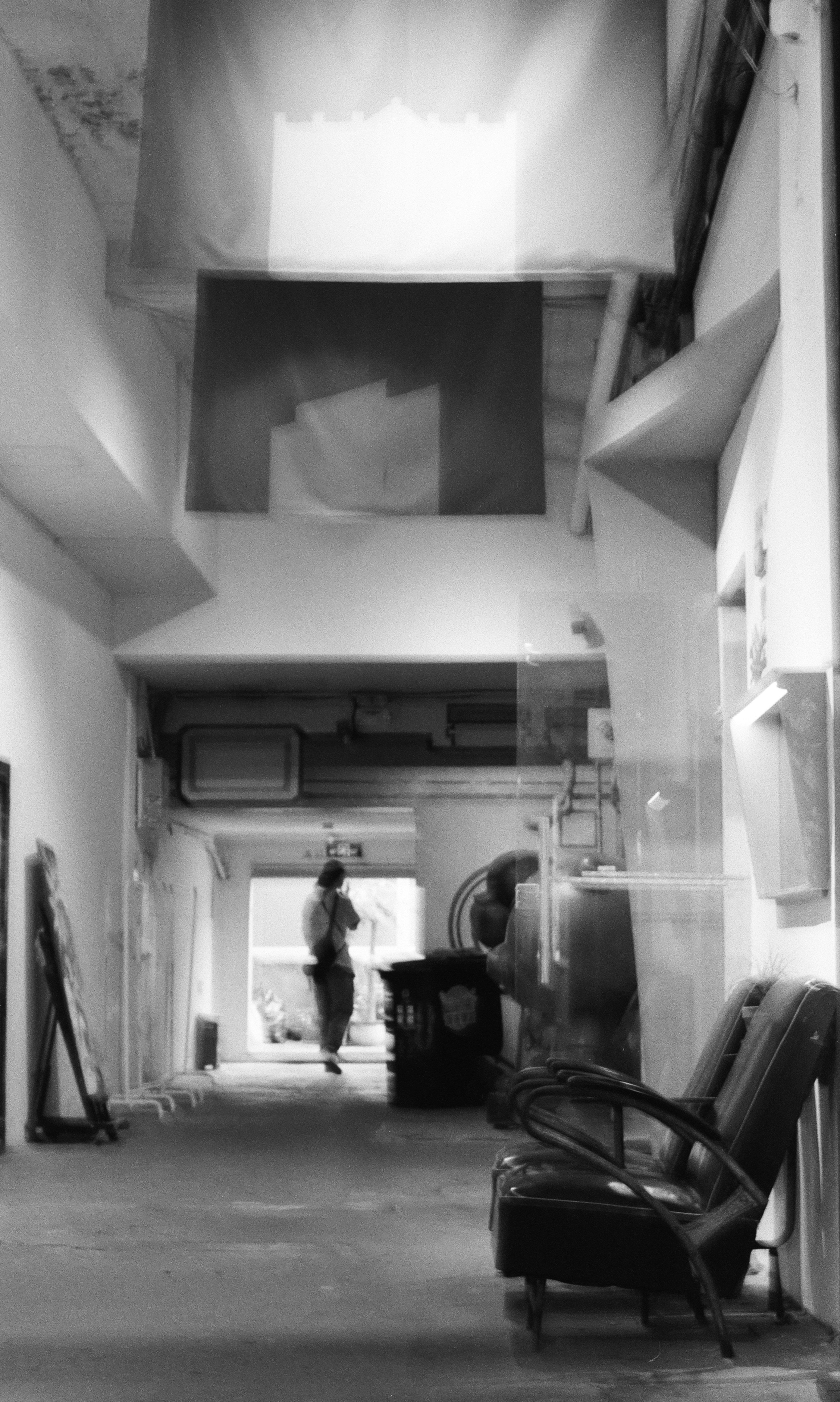 A person walks down a blurred hallway with chairs.