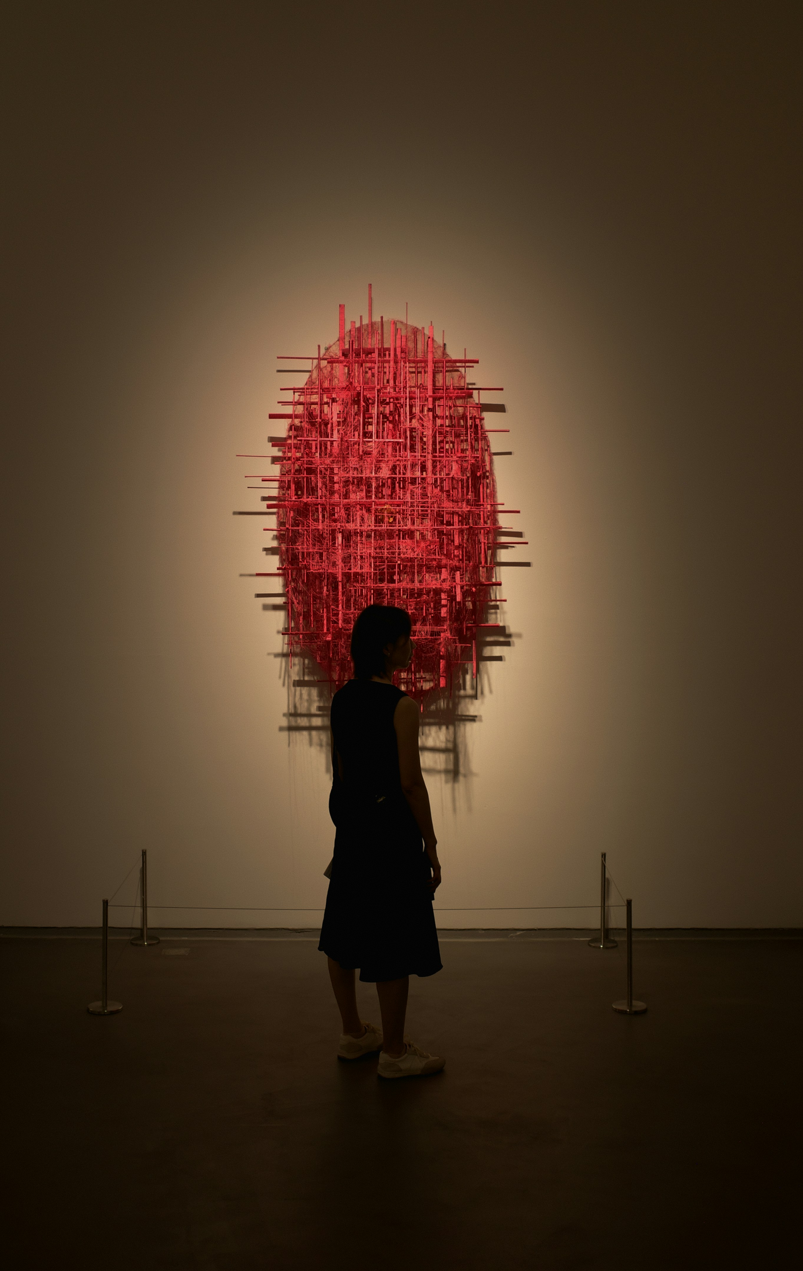 Person observing a large red abstract sculpture