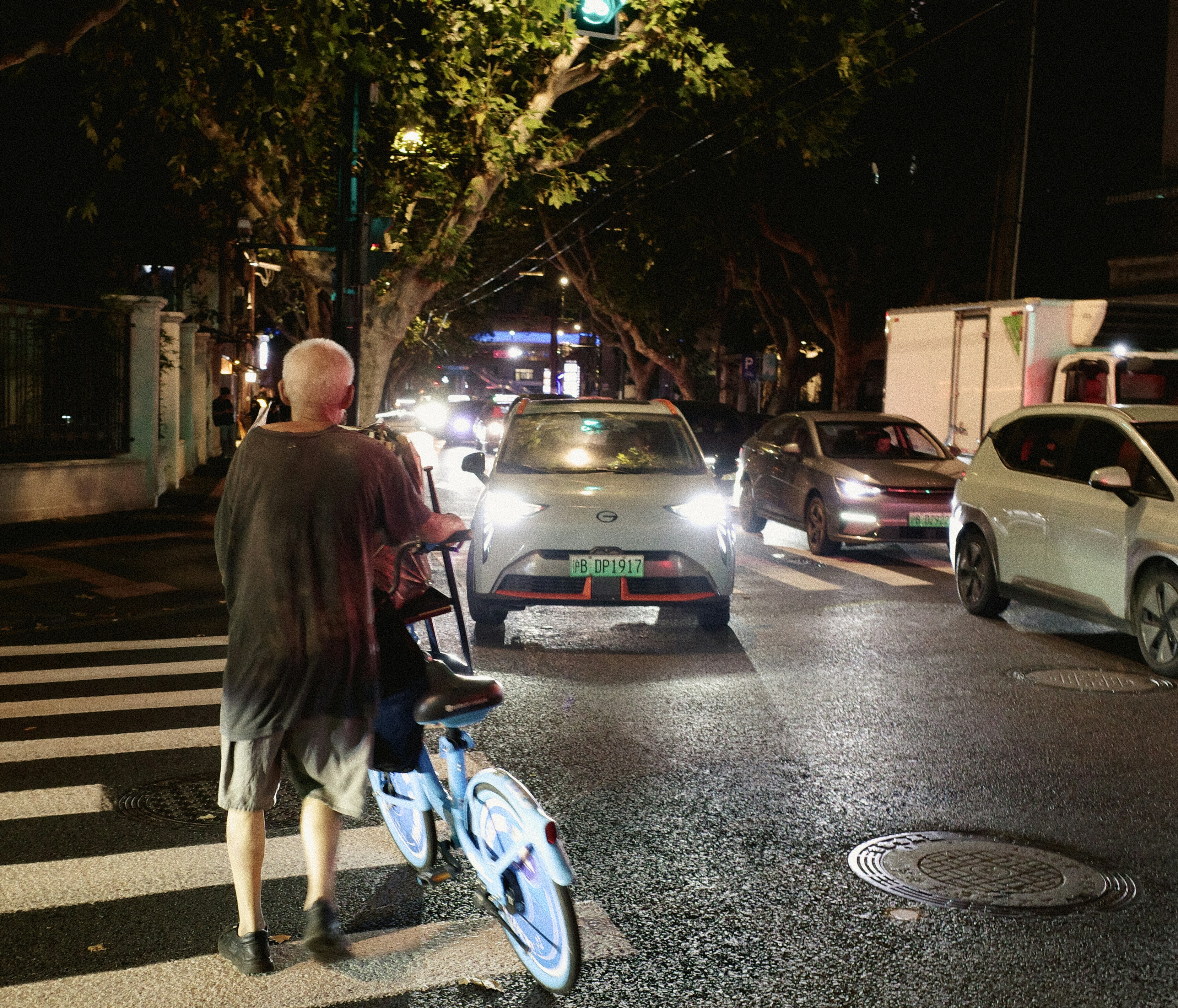 Person with bicycle at crosswalk at night