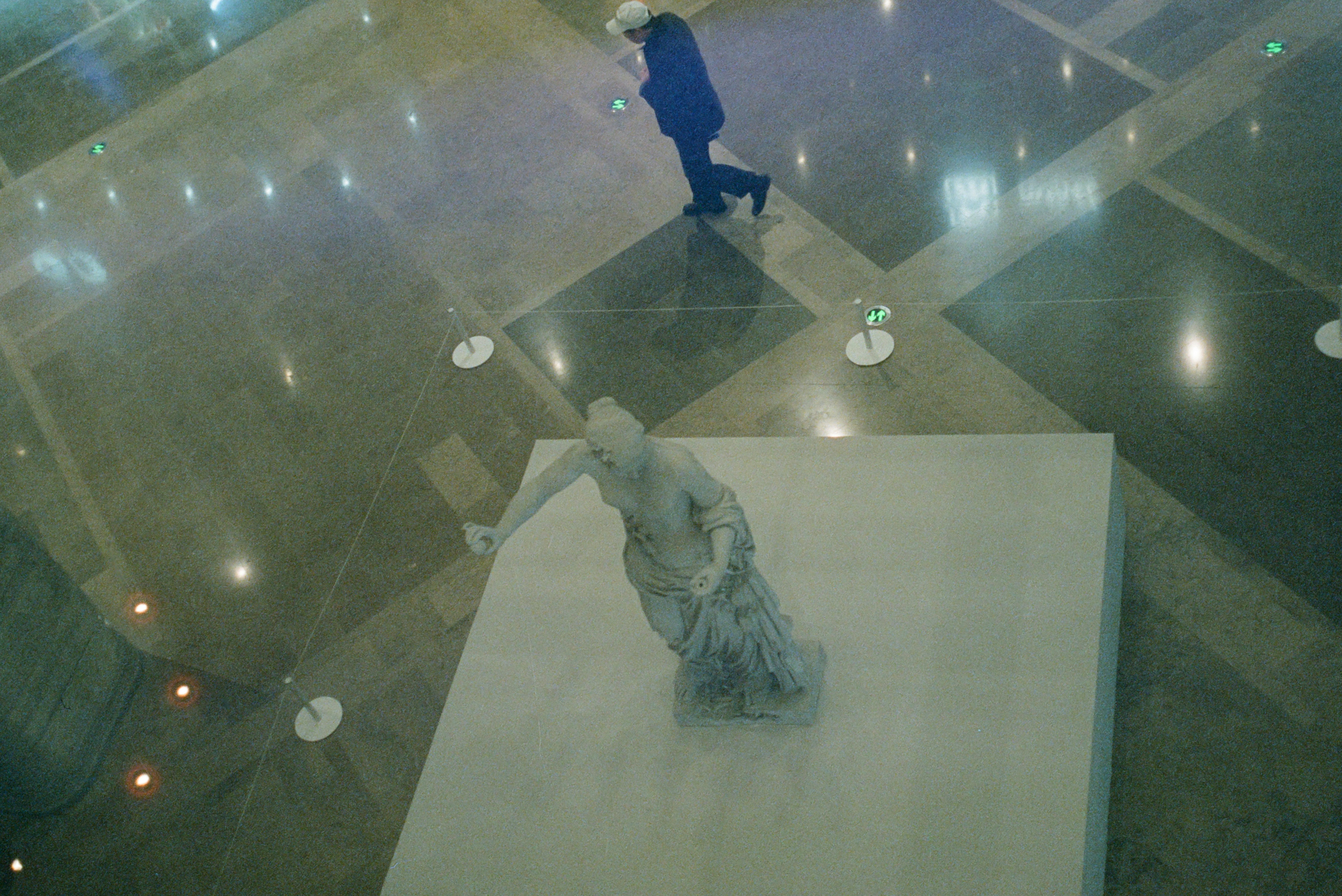Person walks past a statue in a modern hall.