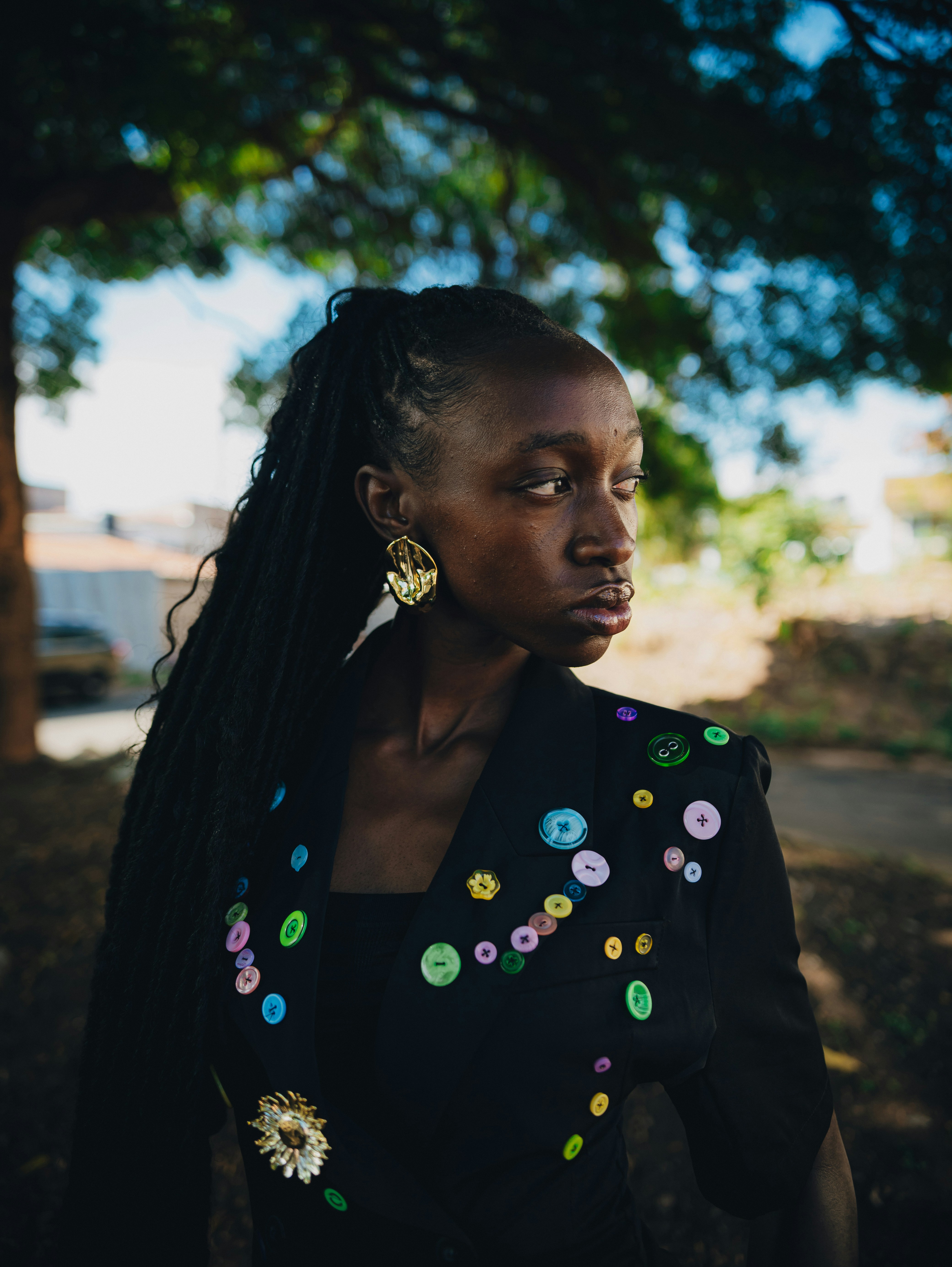 Young black woman with braided hair wearing a decorated blazer.