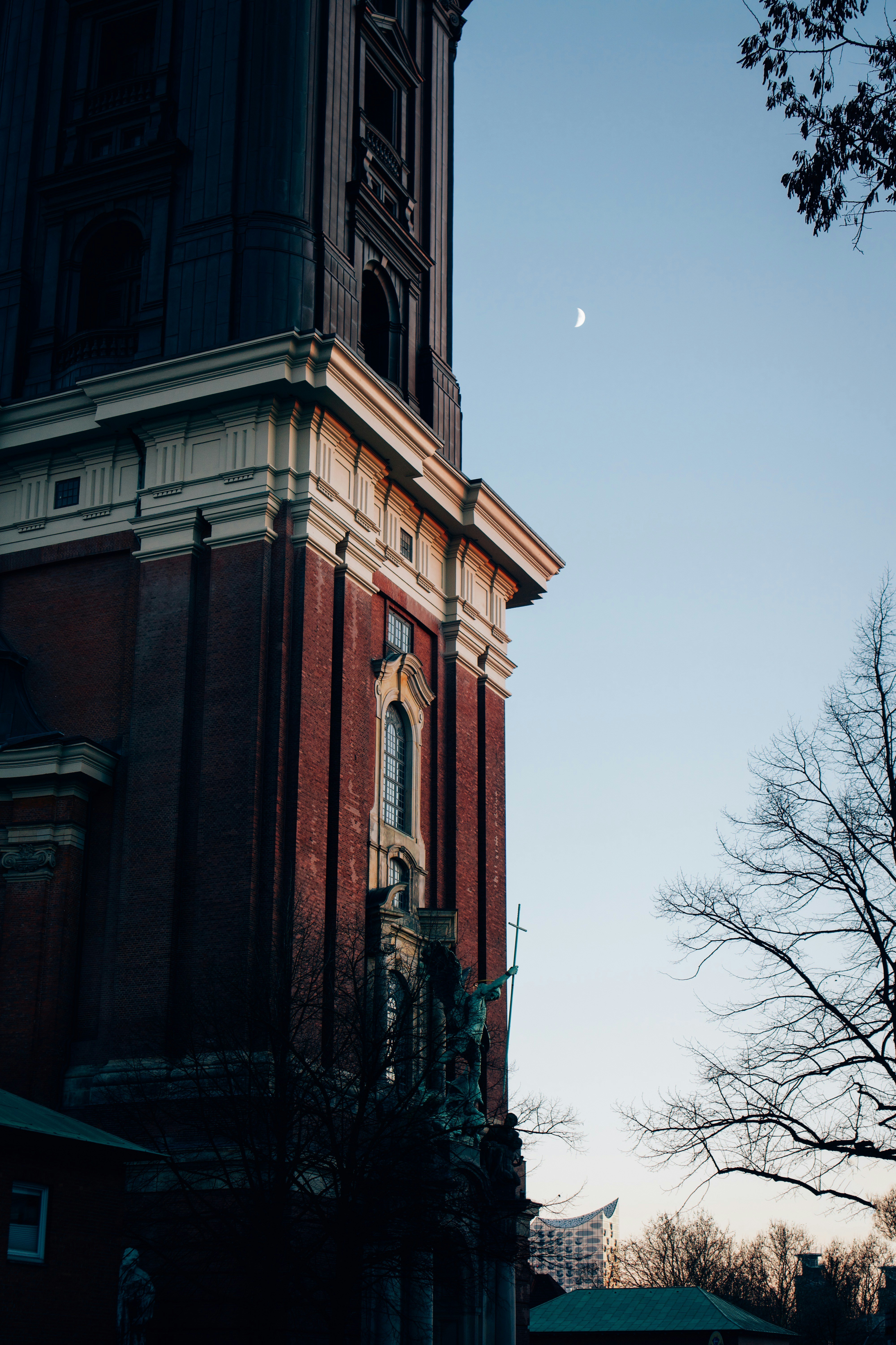 Historic brick church tower with crescent moon in sky.