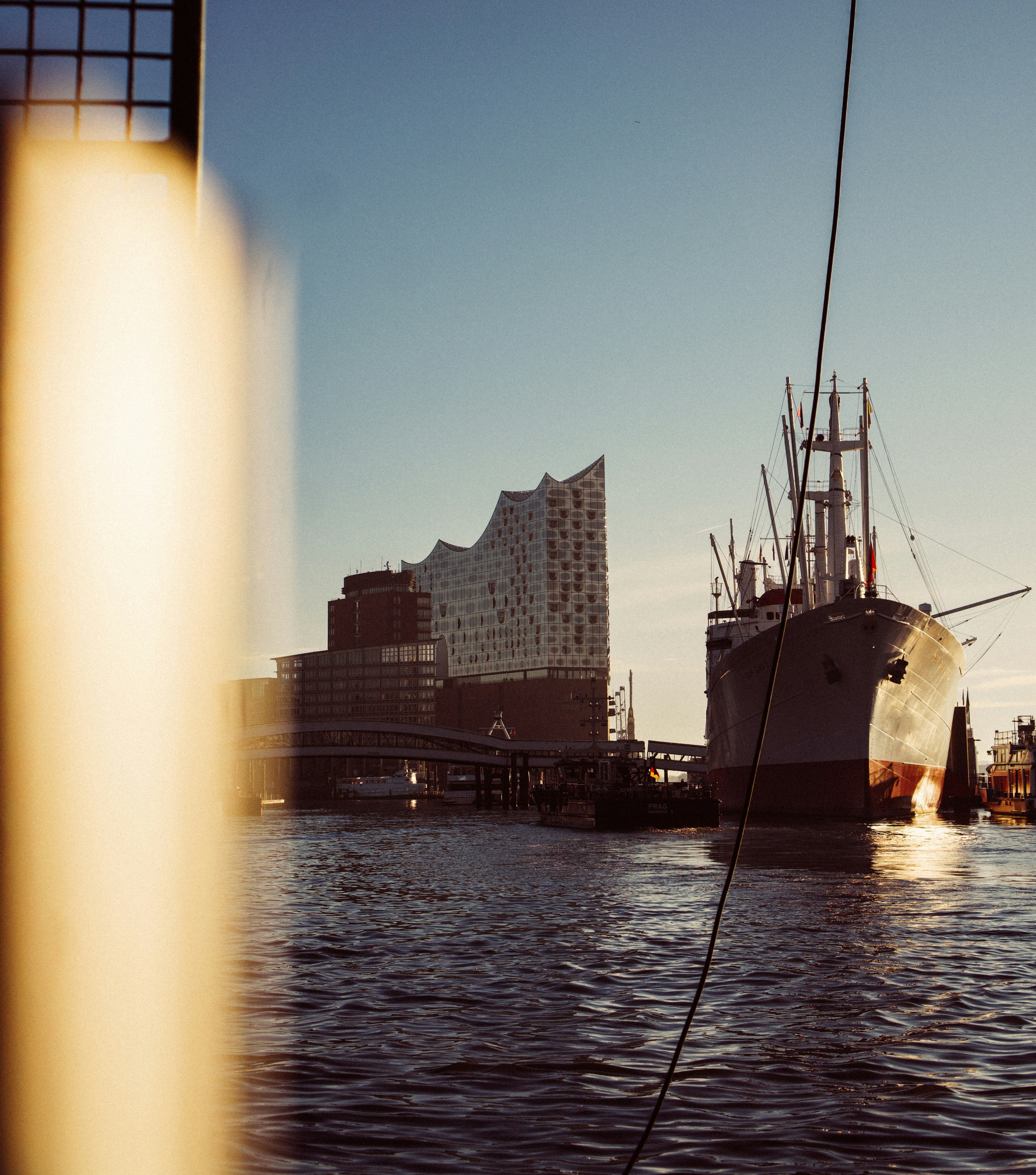 Ship docked near a modern building by the water.