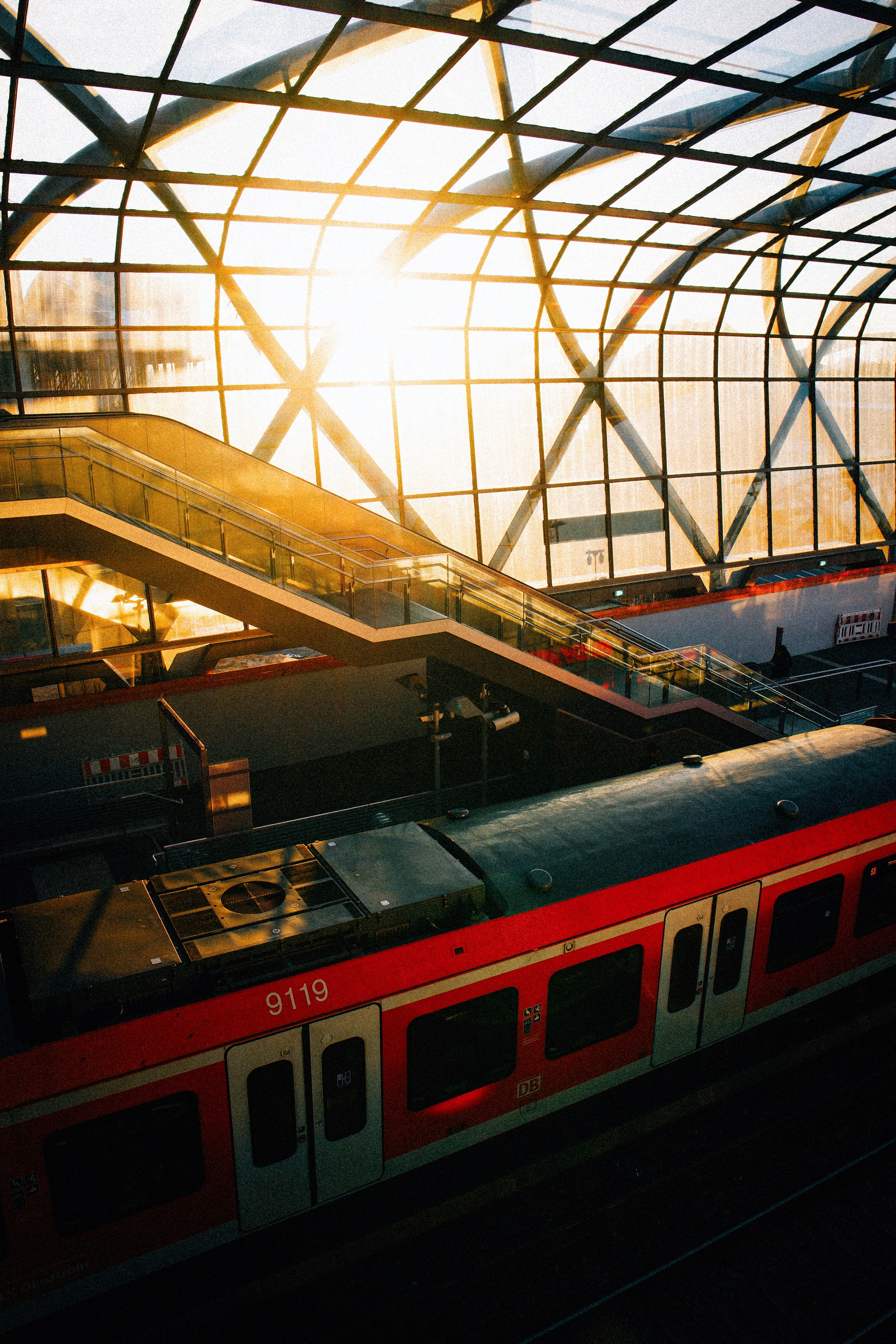 Trains at a station with sun shining through roof.