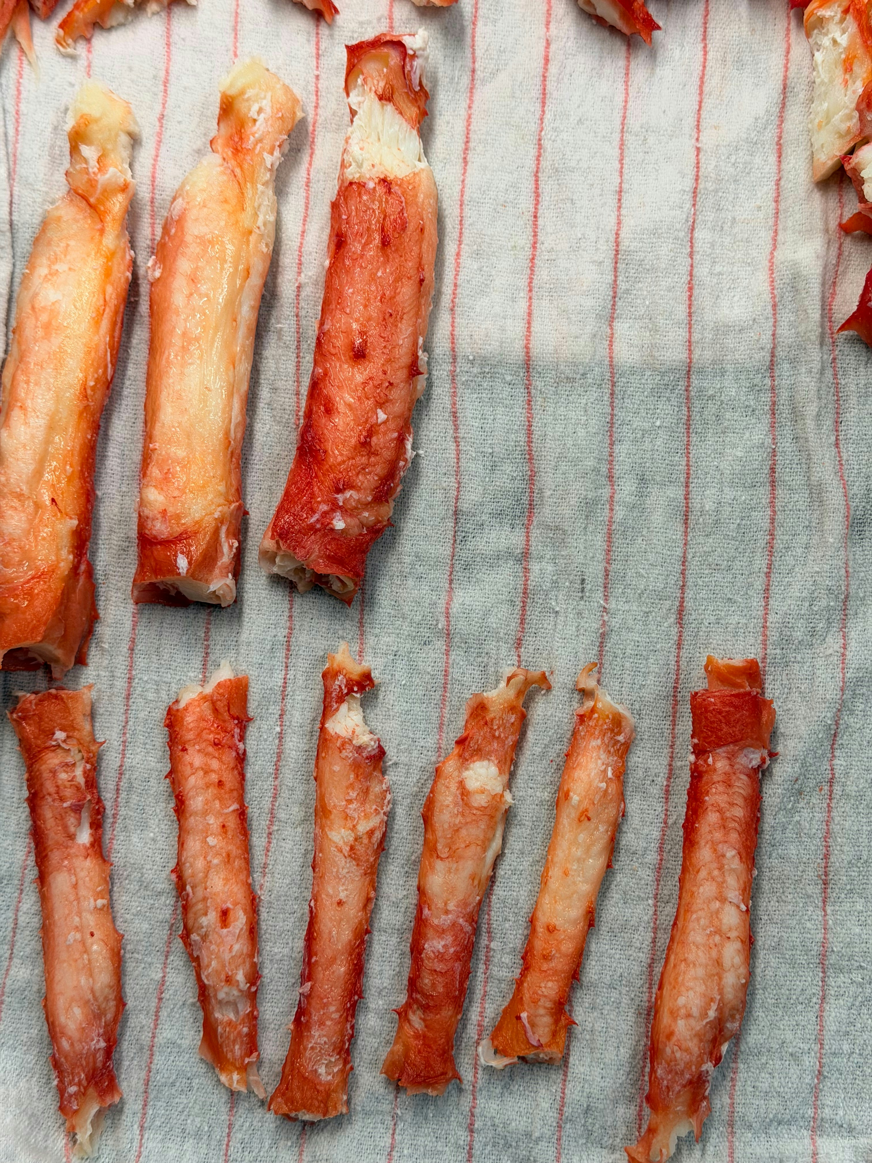 Cooked crab legs arranged on a striped cloth.