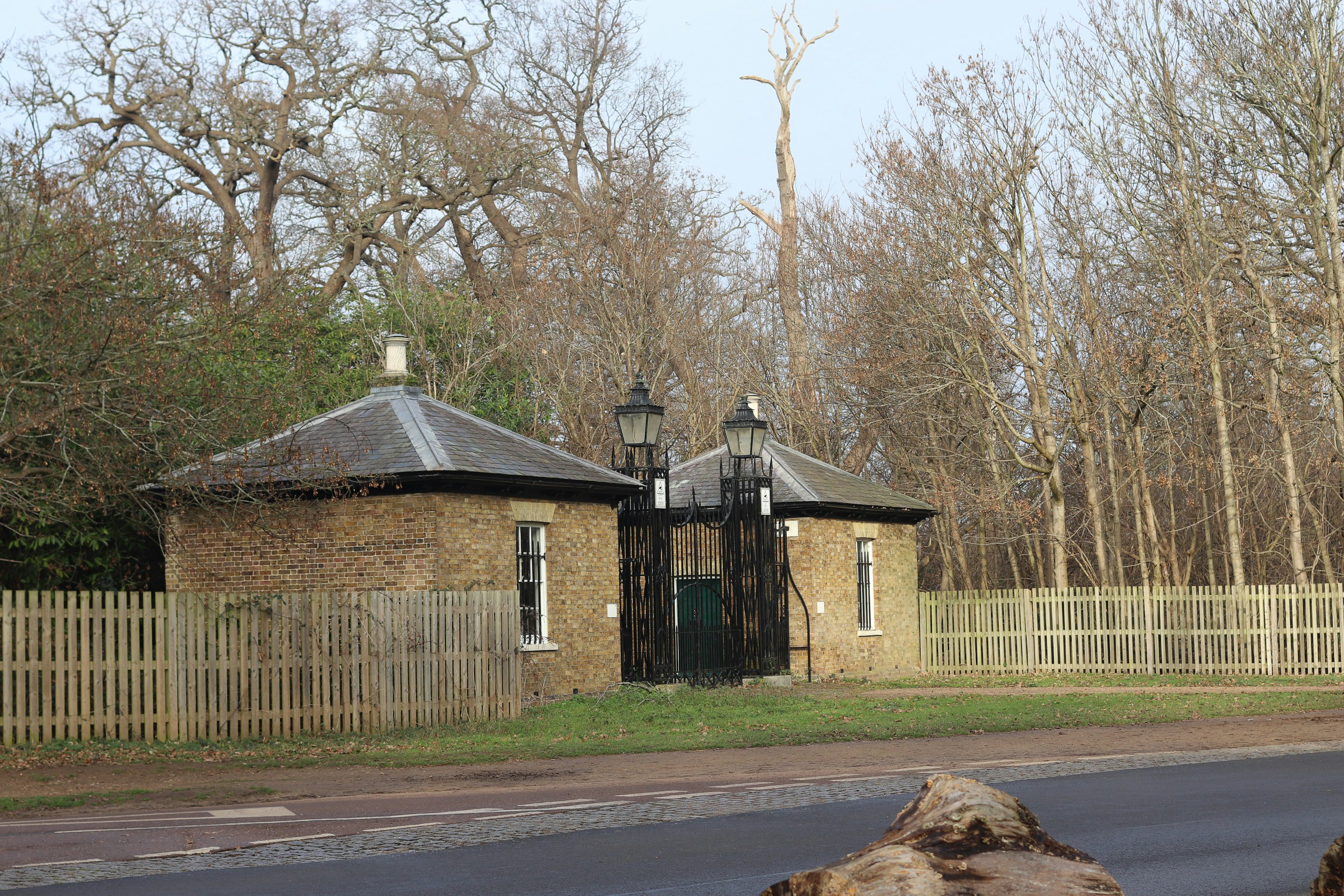 Two brick gatehouses with an ornate gate between them.