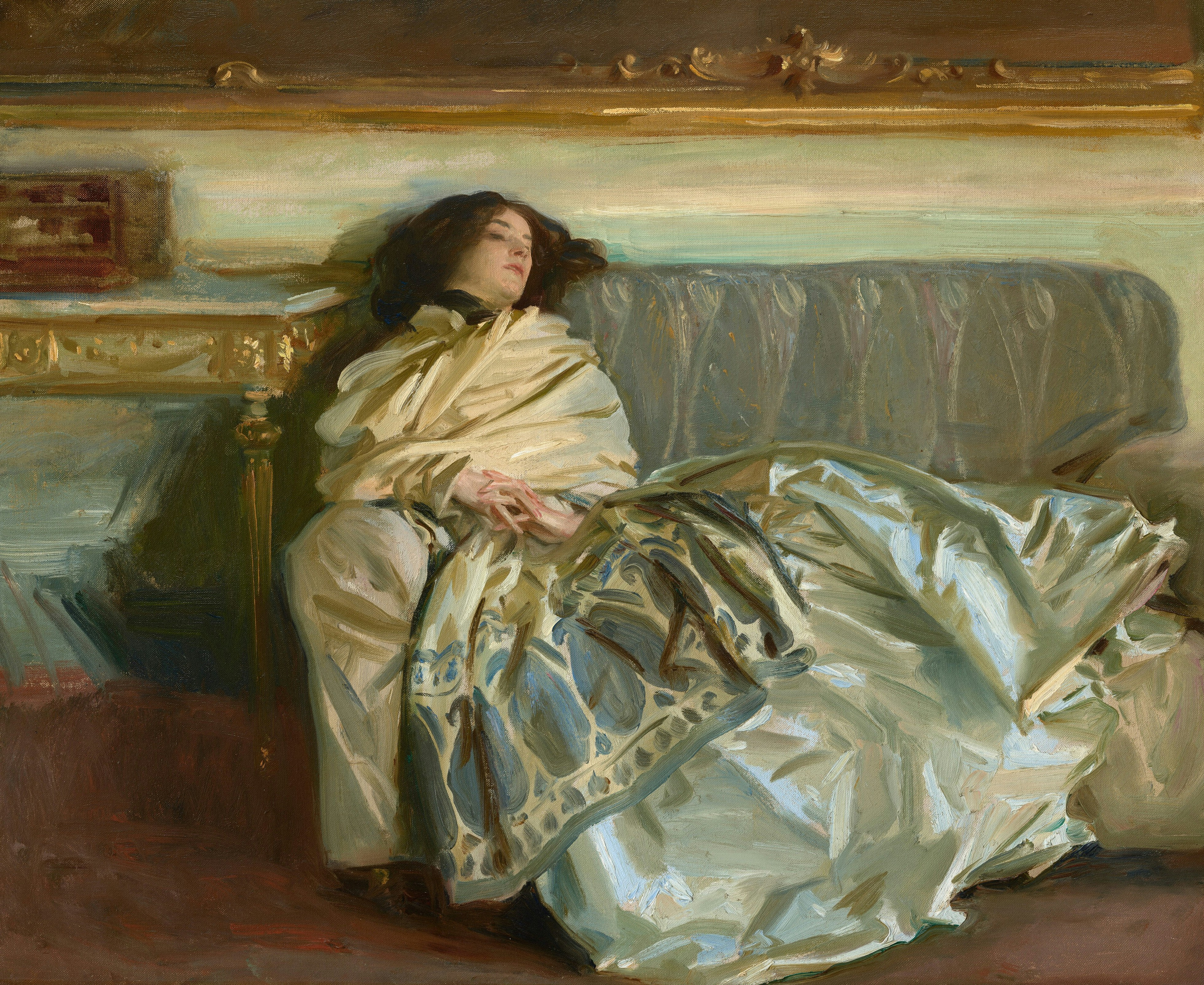 Eine Frau, die auf einem Sofa in einen Schal gehüllt liegt.