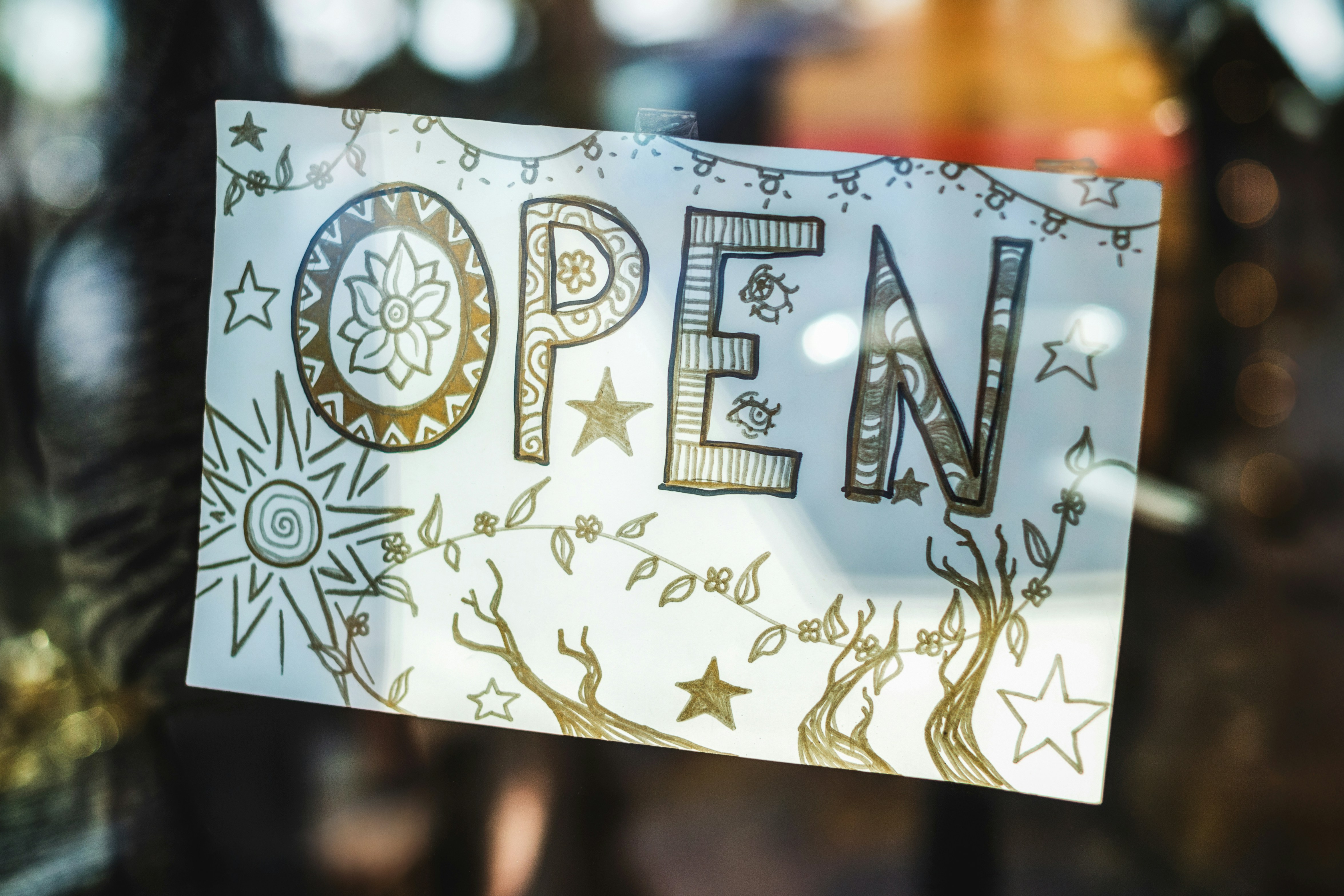 Insegna aperta disegnata a mano con elementi decorativi.