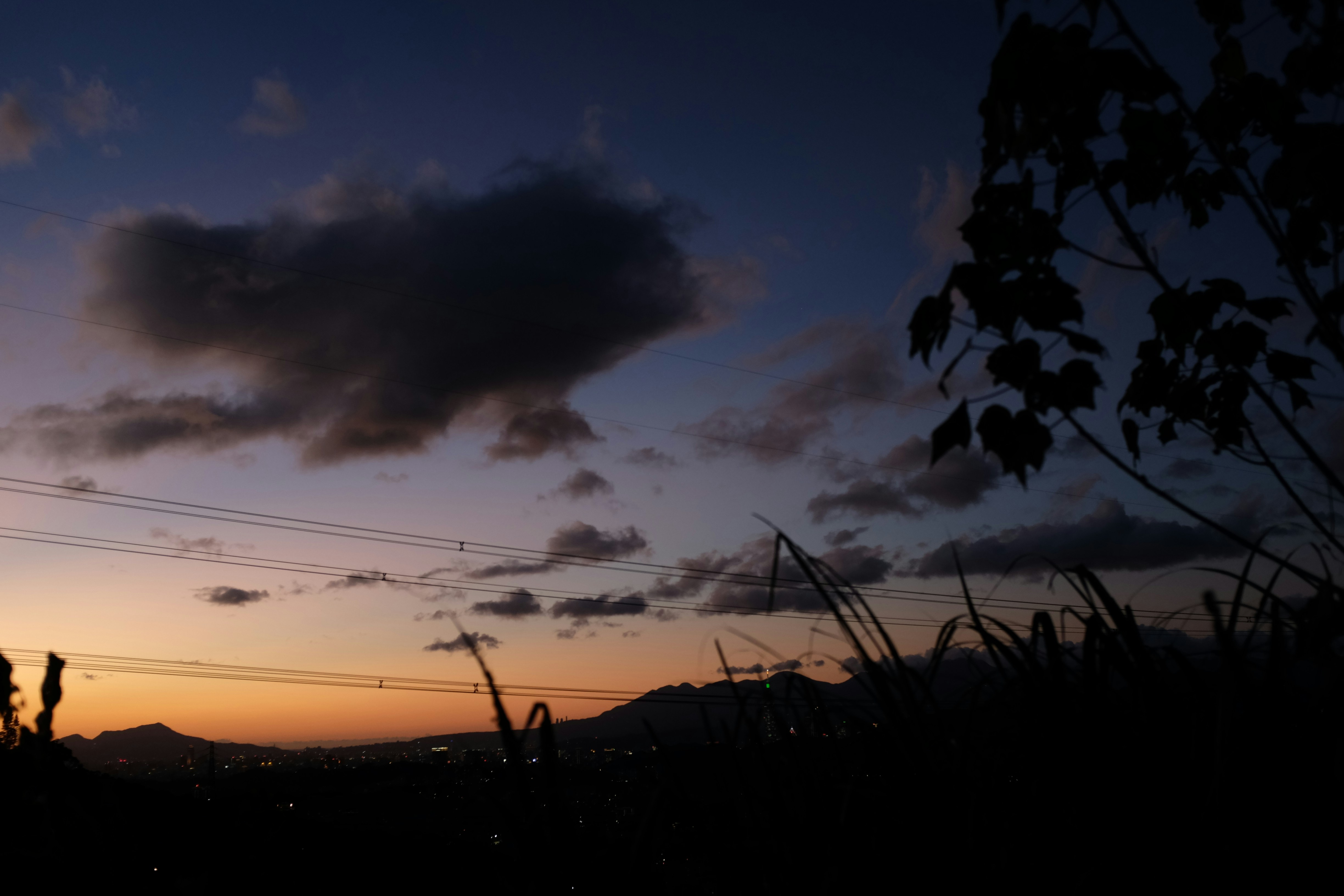 Dusk sky with clouds over a silhouetted landscape.