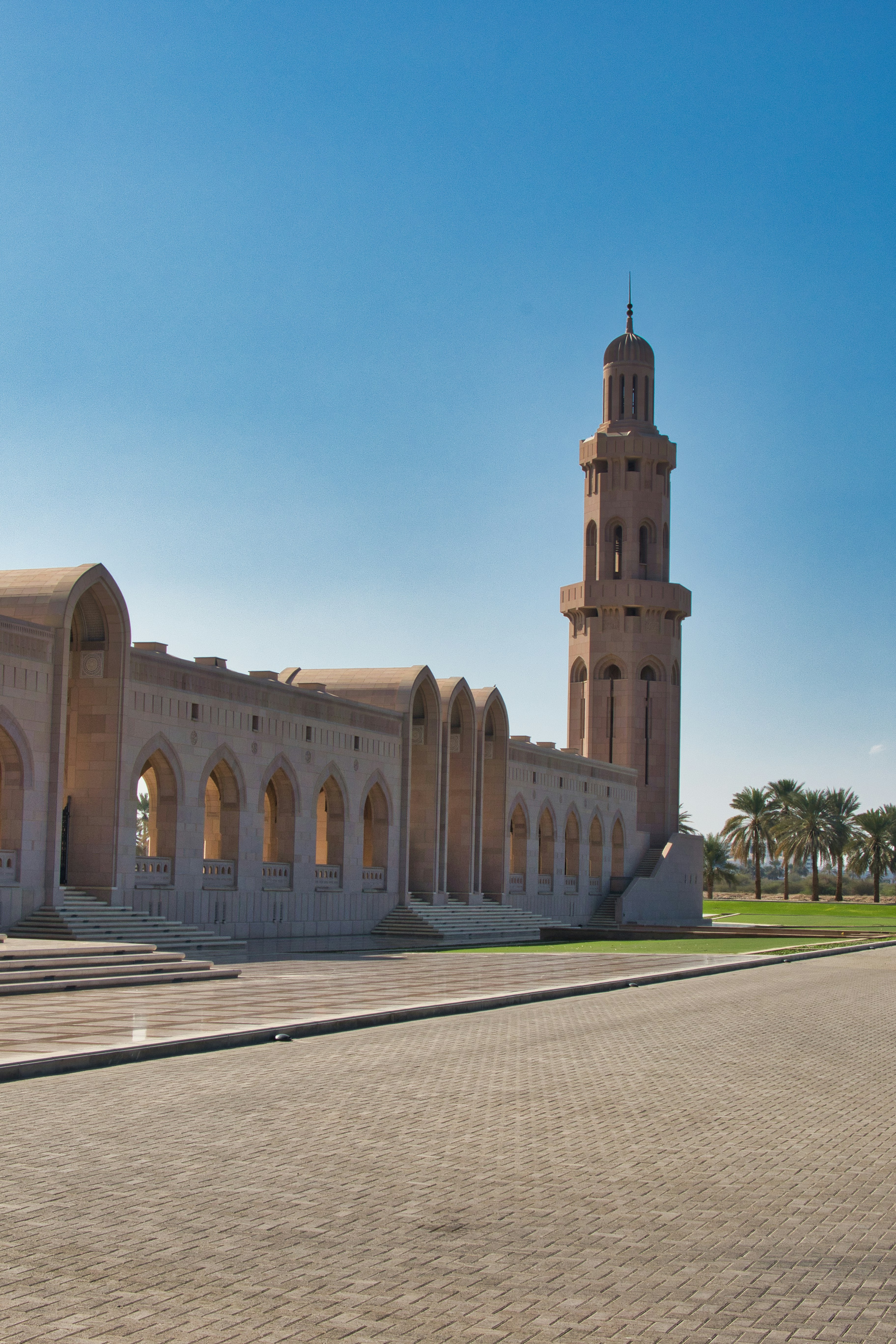 A grand mosque with a tall minaret under blue sky.