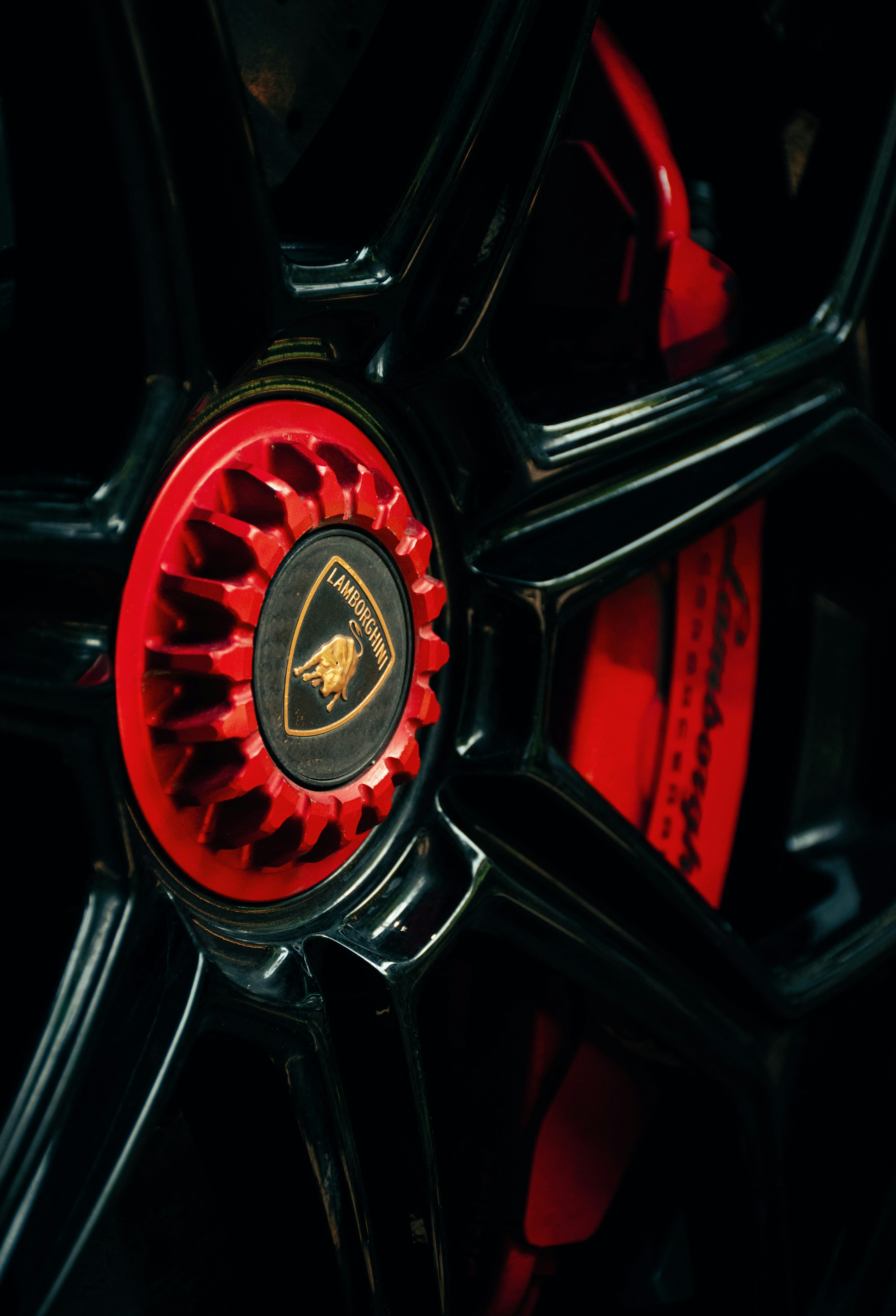 Close-up of a black lamborghini wheel with red brake caliper.