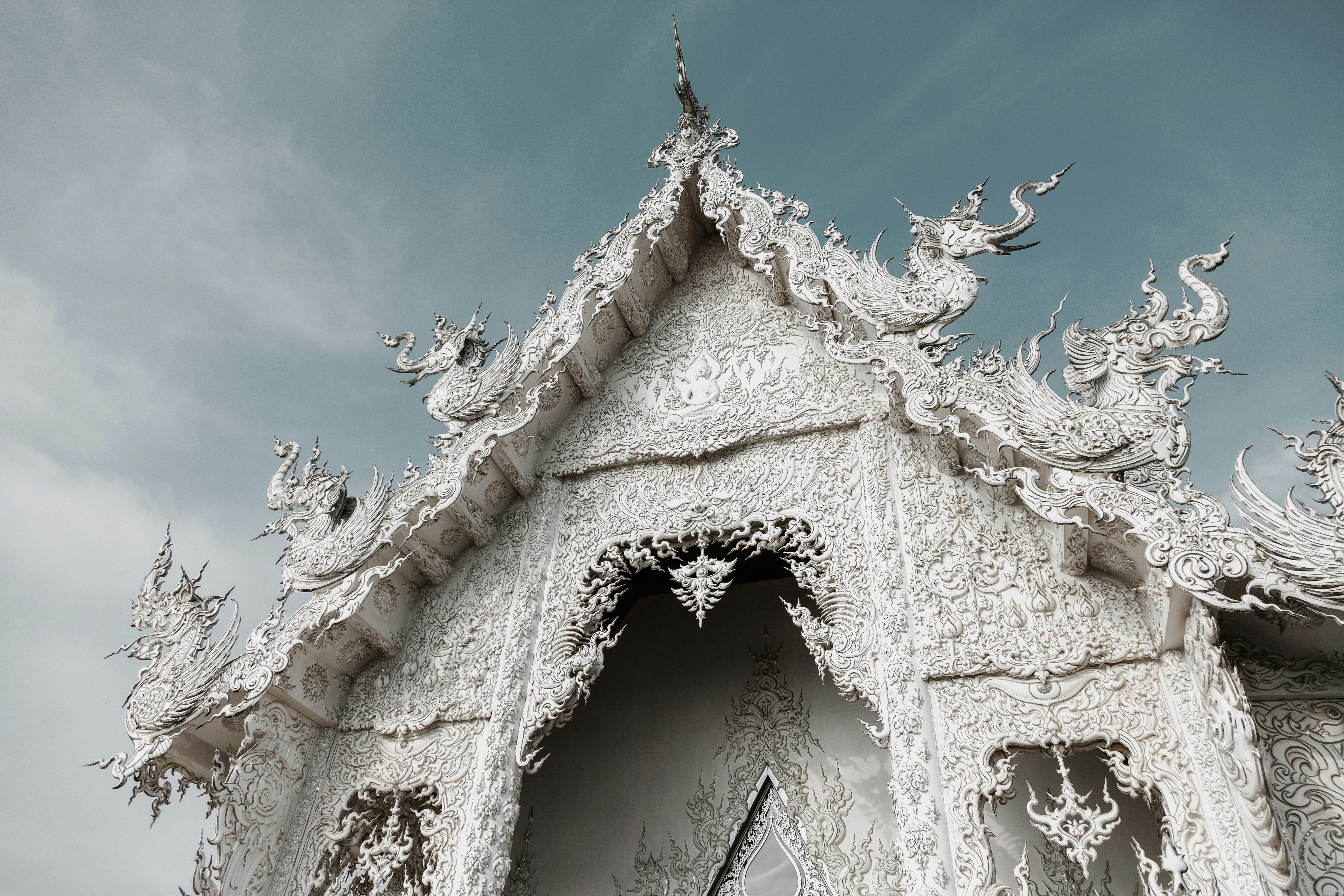 Ornate white temple roof against a cloudy sky