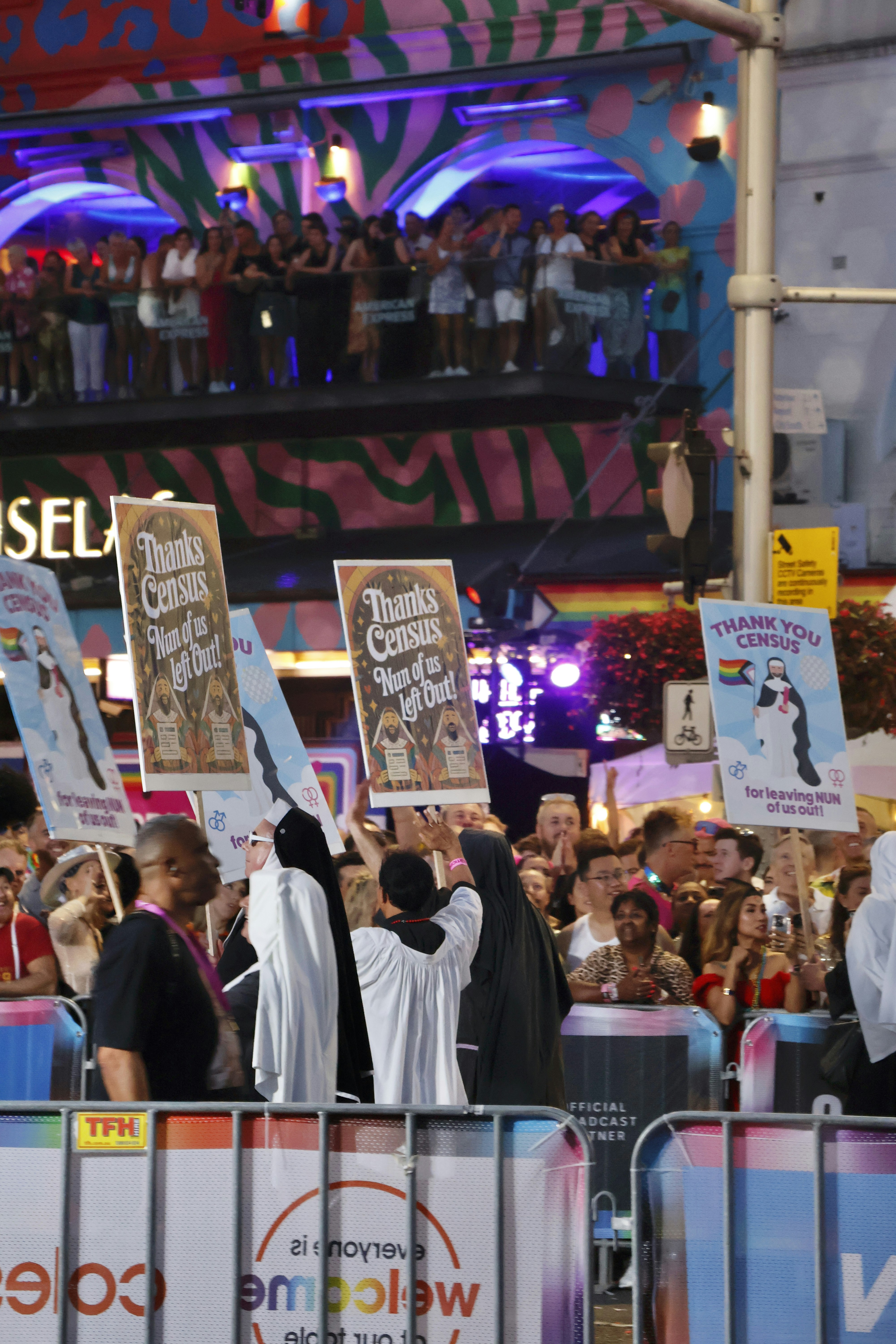 People holding signs at a vibrant street celebration