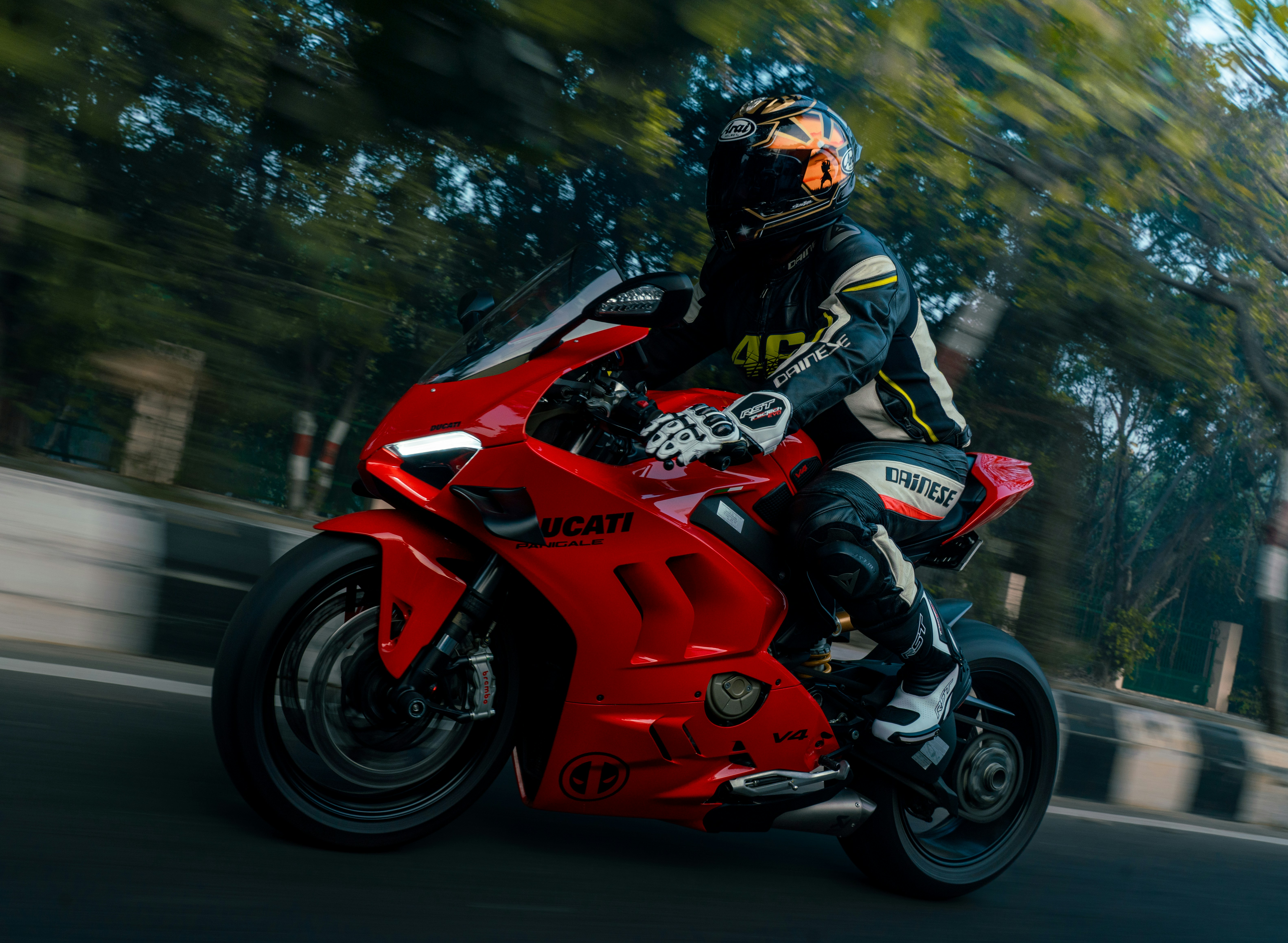 Man in racing gear riding a red motorcycle on road