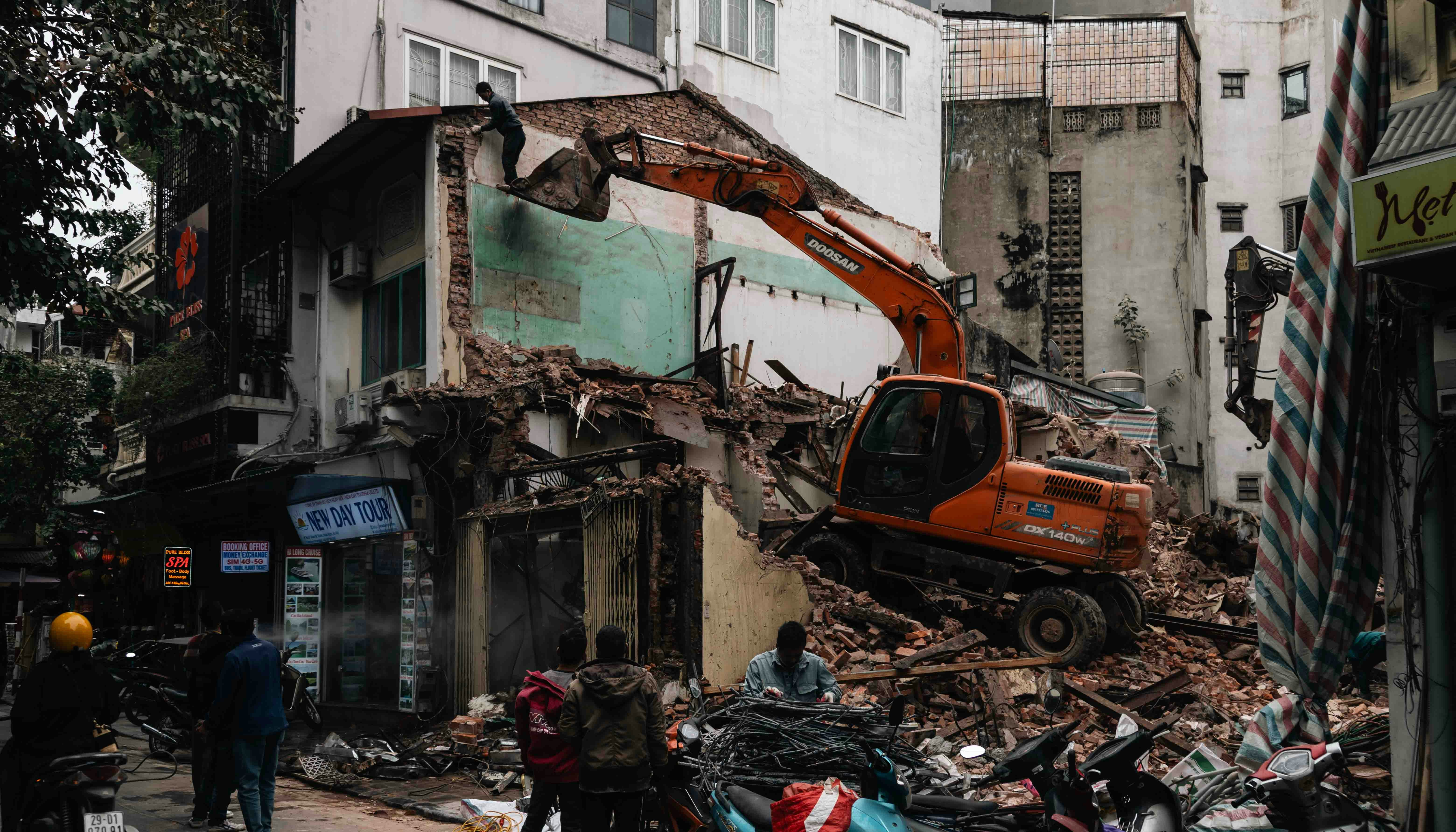 ショベルカーが瓦礫や瓦礫の中、建物を破壊する様子。