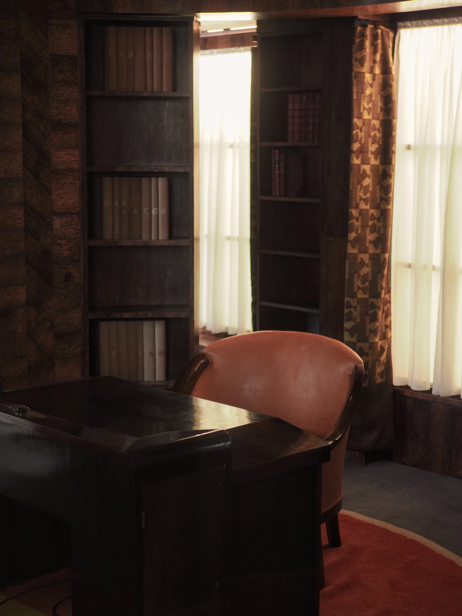 A warm study with bookshelves, a desk and reading chair