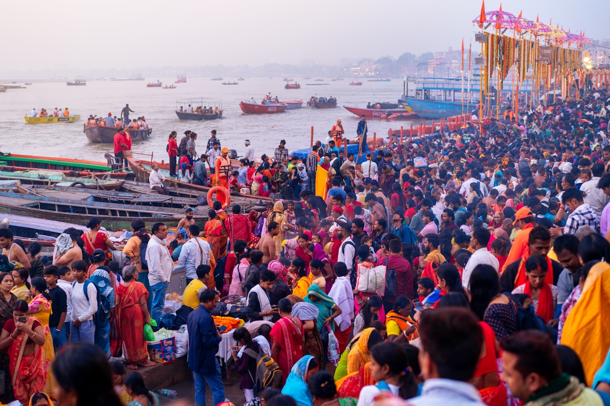 Crowded riverbank along the Ganges with boats, devotees and evening light