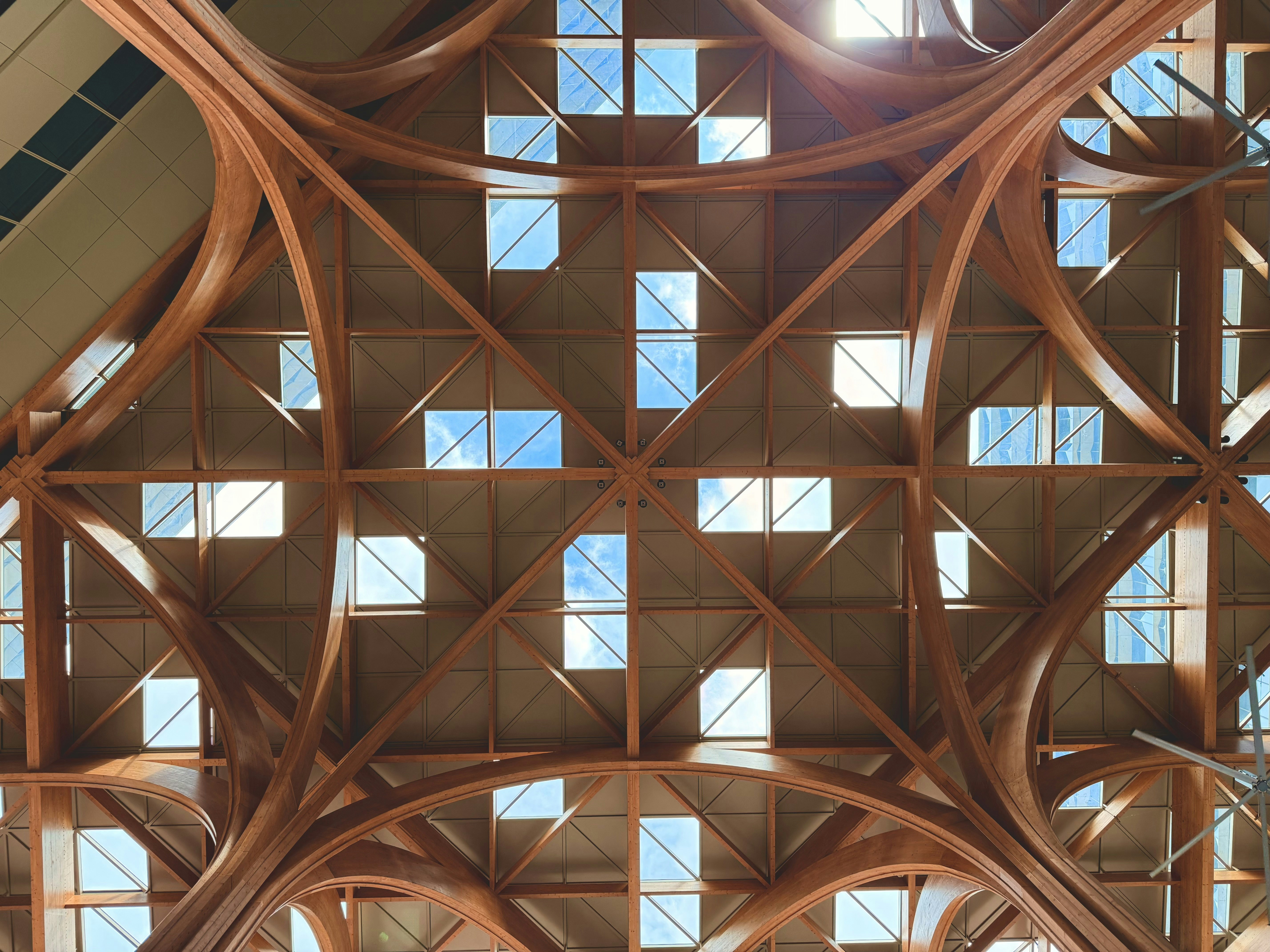 A brightly lit overhead shot of architectural blueprints spread out on a wooden table next to a pen and coffee, symbolizing home renovation planning.