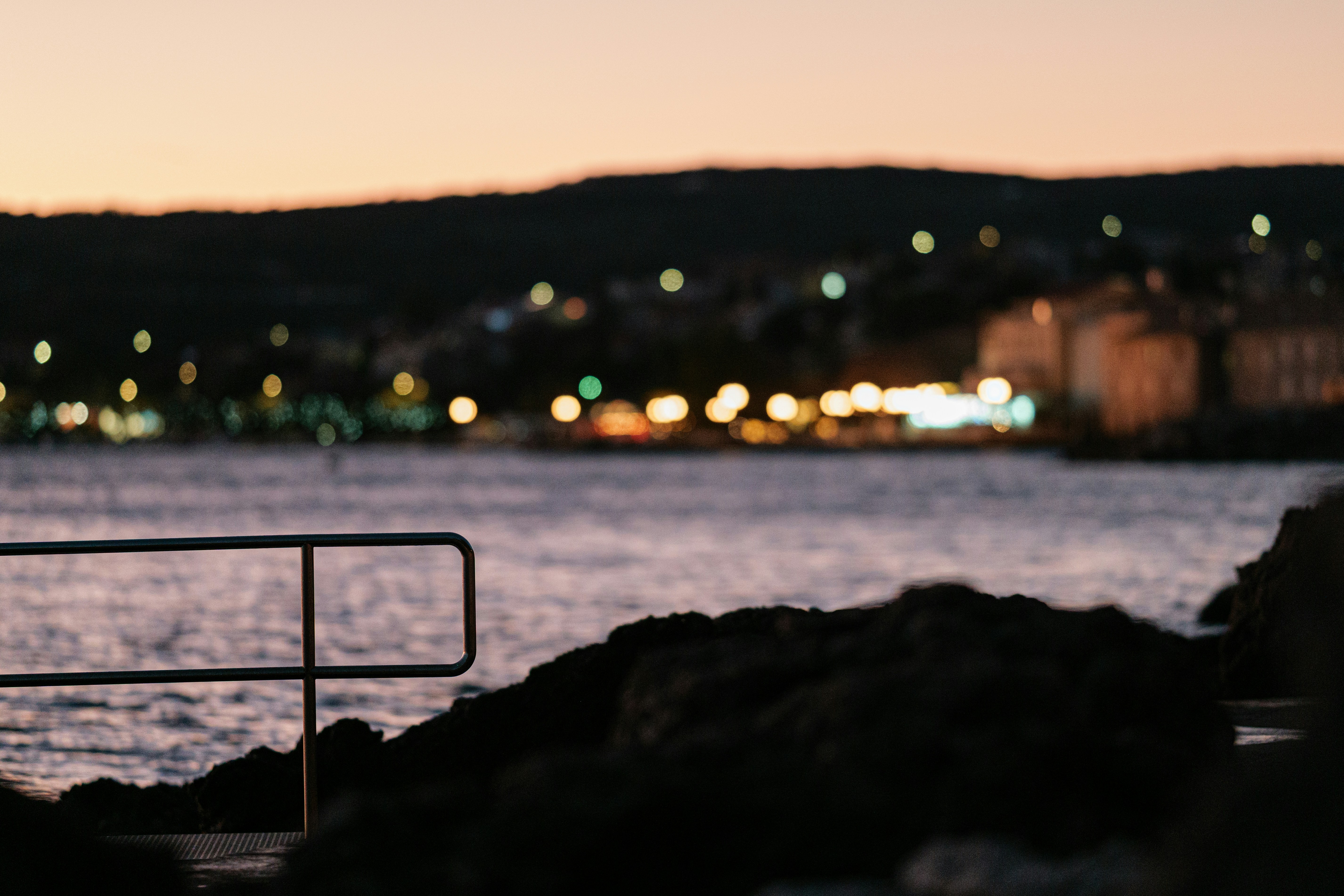 Lumières lointaines de ville à travers l’eau au crépuscule