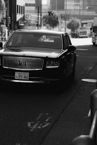 A black luxury car drives down a city street.