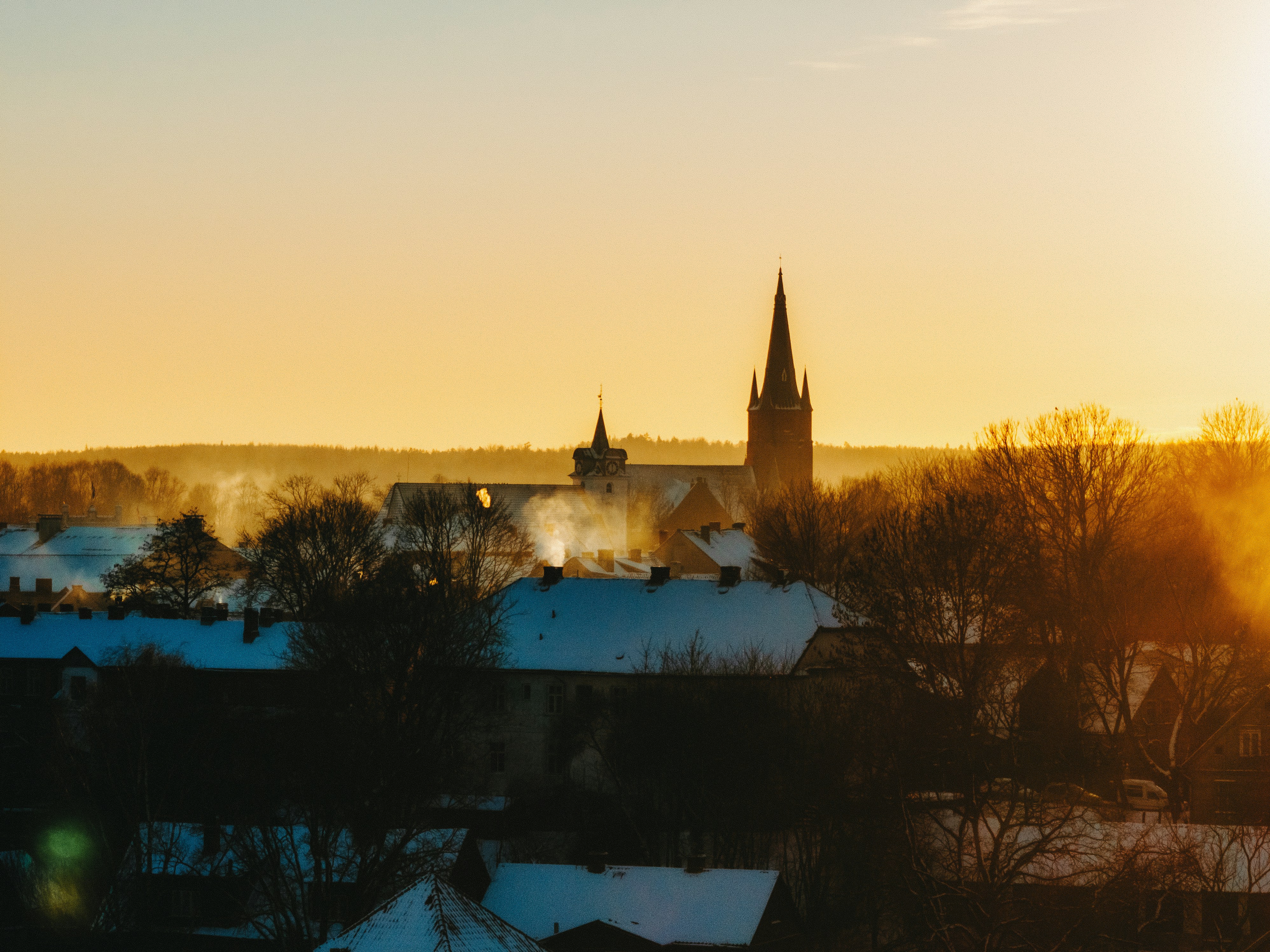 Winter village with church steeple at sunrise.
