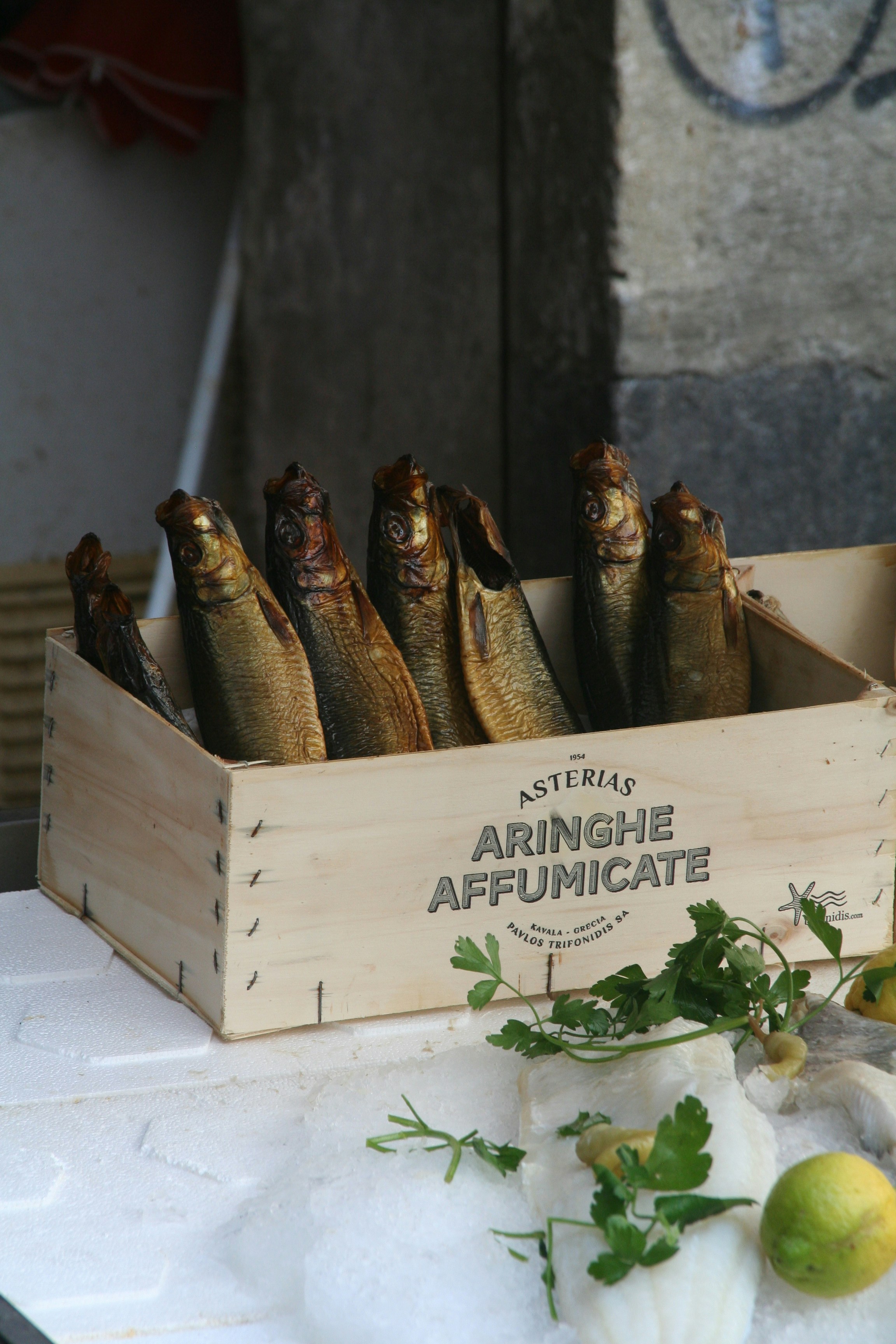 Smoked herring in a wooden crate with herbs.