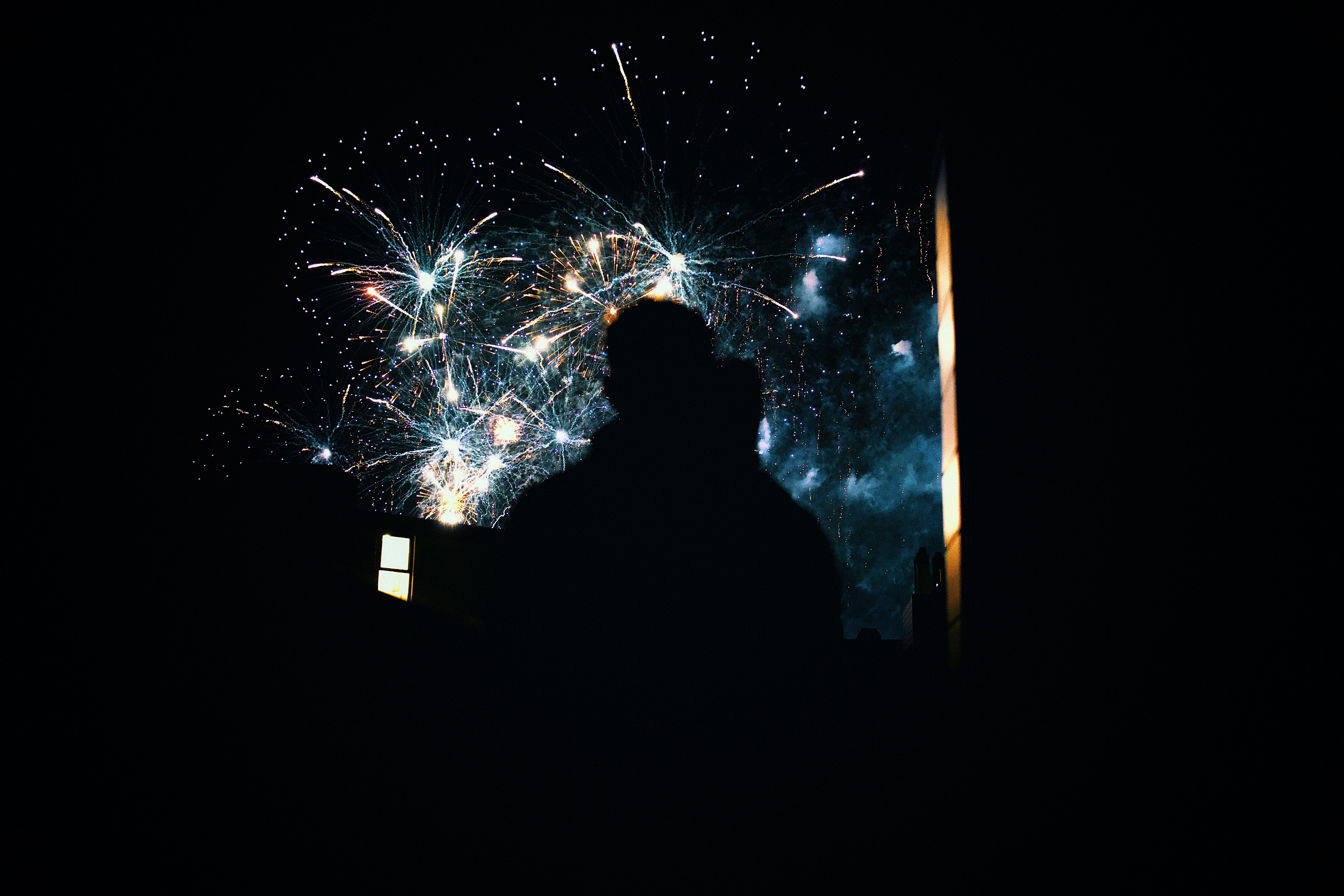 Silhouettes of people watching fireworks display