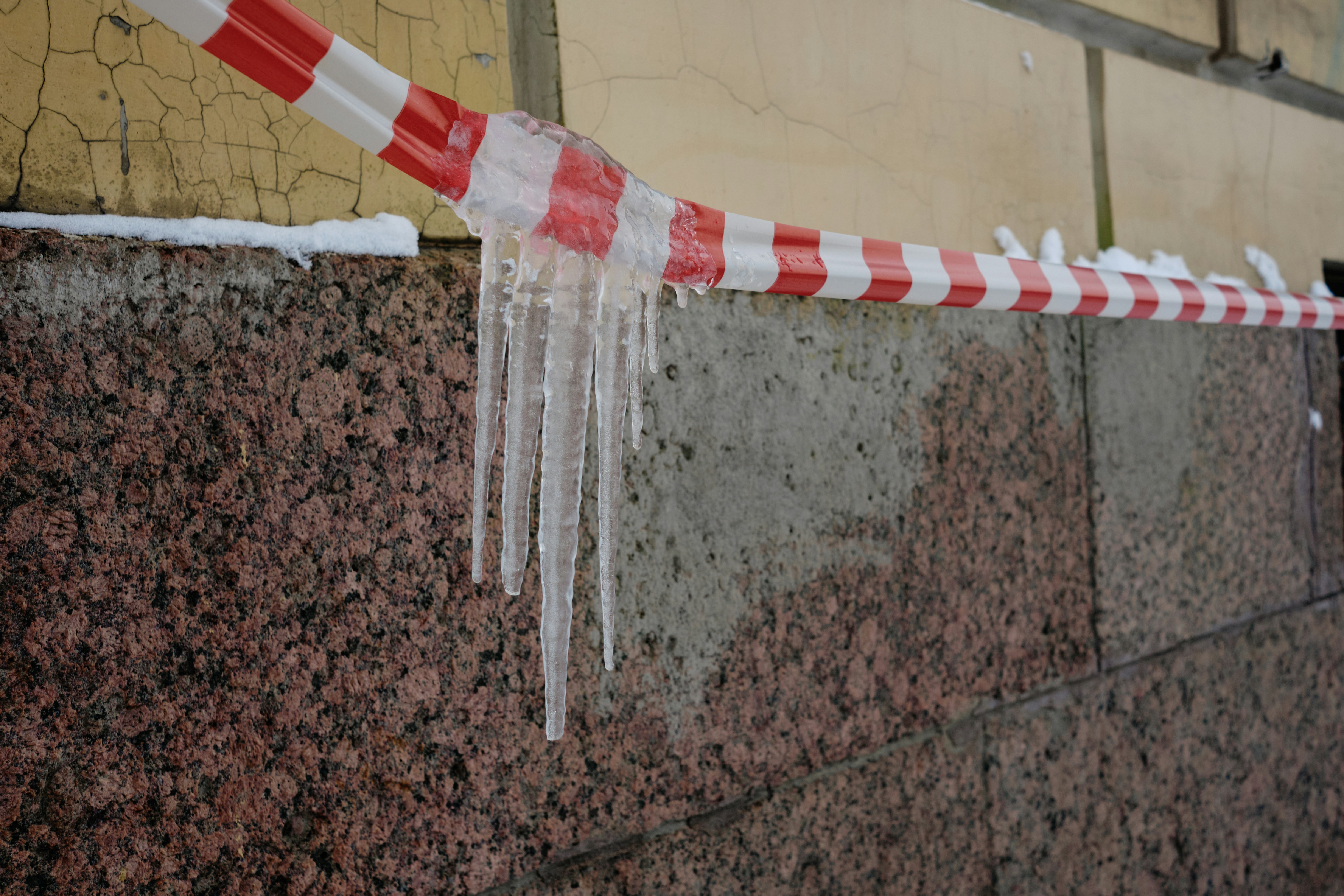 Icicles hang from a red and white striped caution tape.