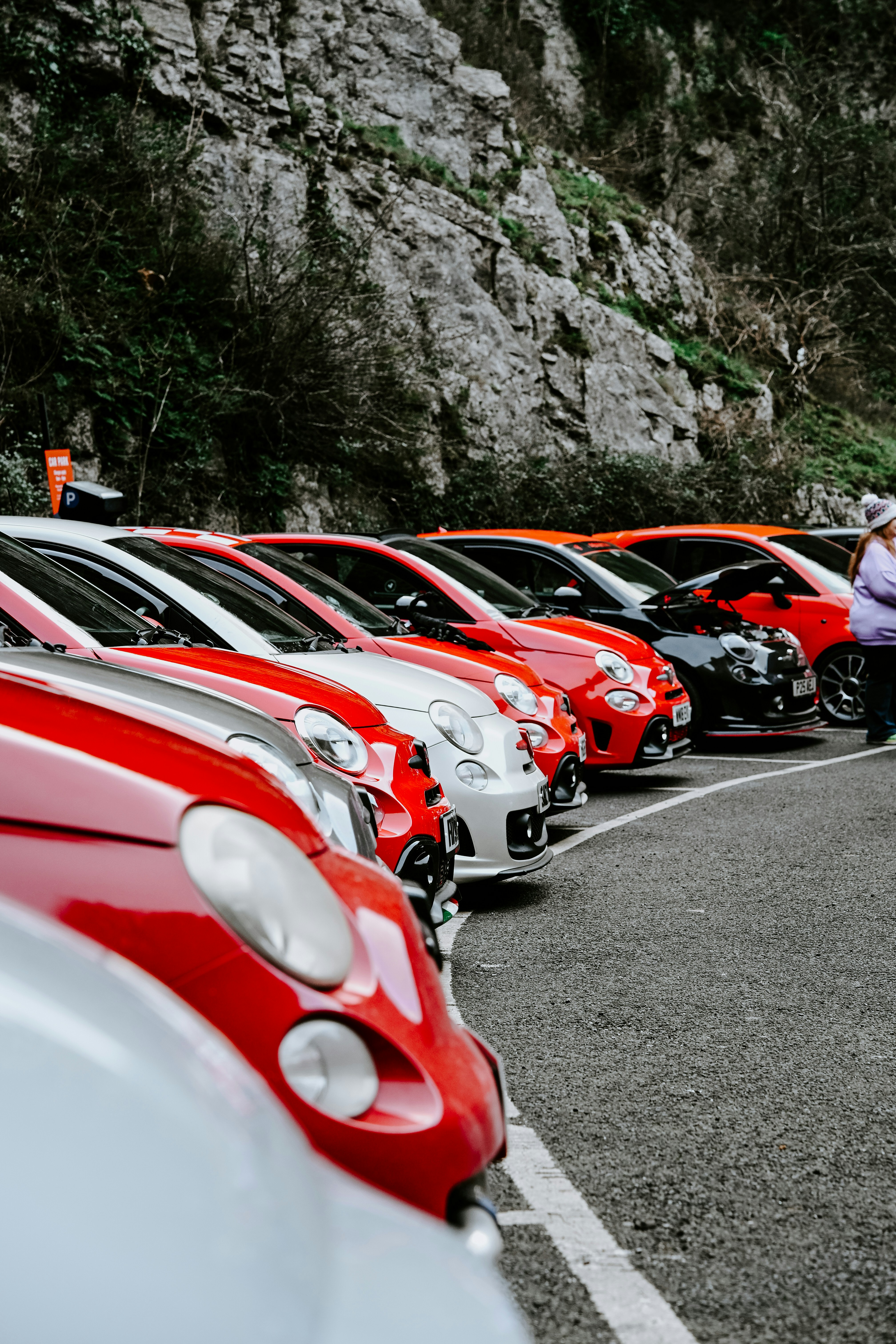 Fileira de carros vermelhos e brancos estacionados junto ao penhasco