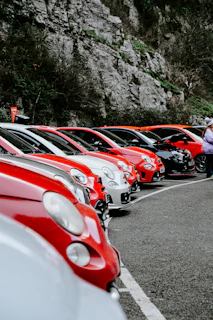 Line of red and white cars parked by cliff