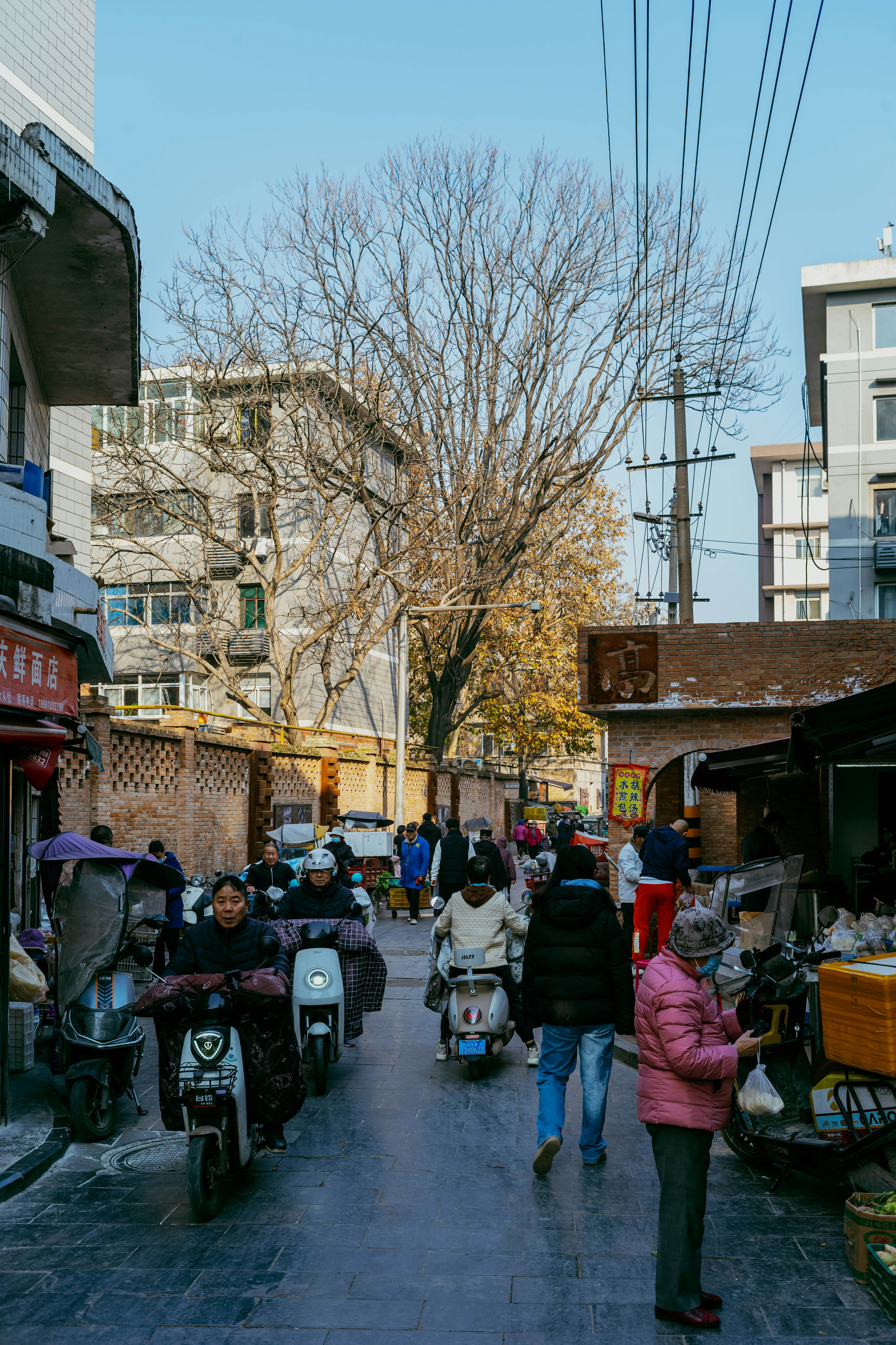 People riding scooters down a busy street.