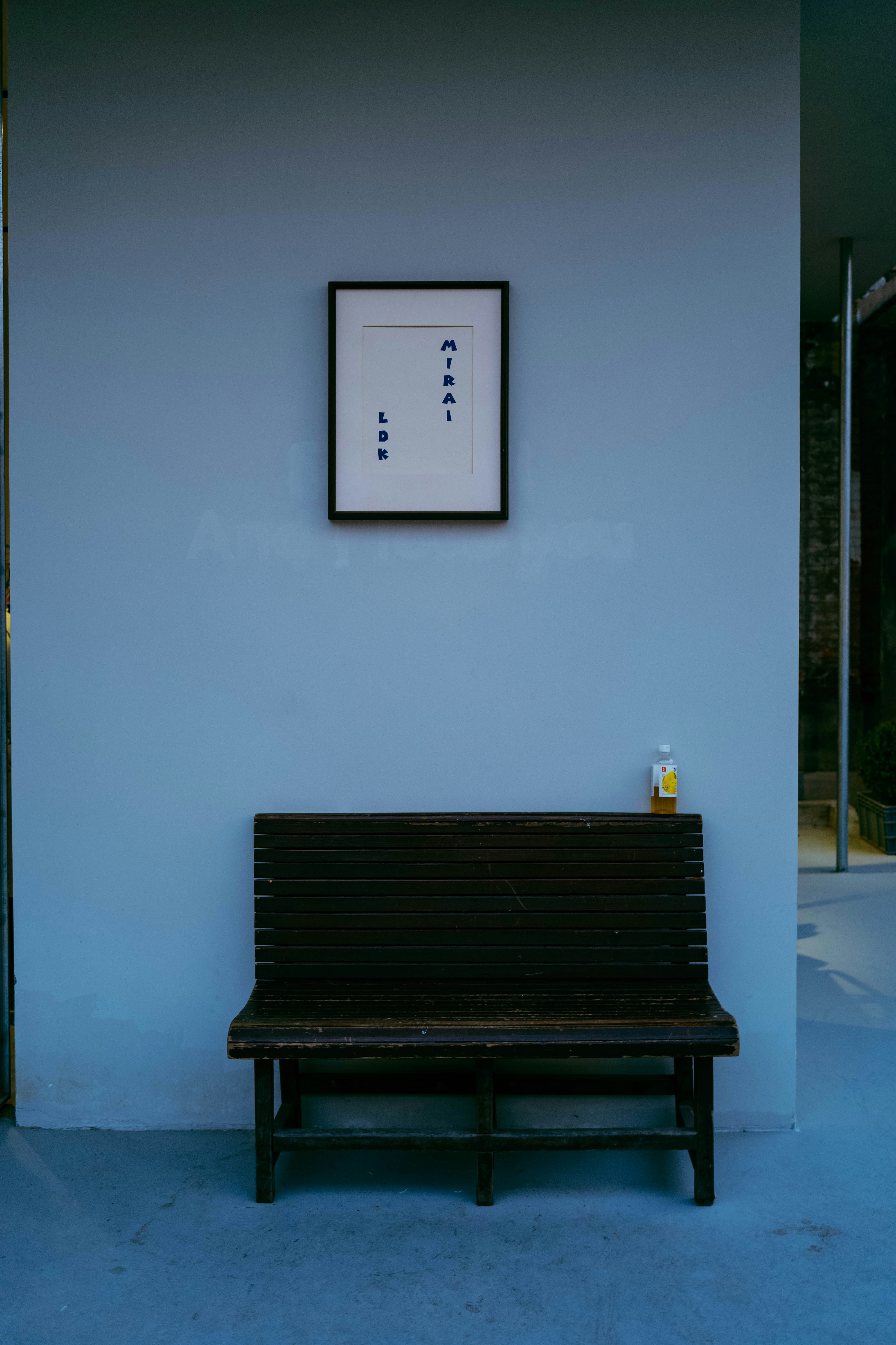 A framed artwork hangs above a wooden bench.