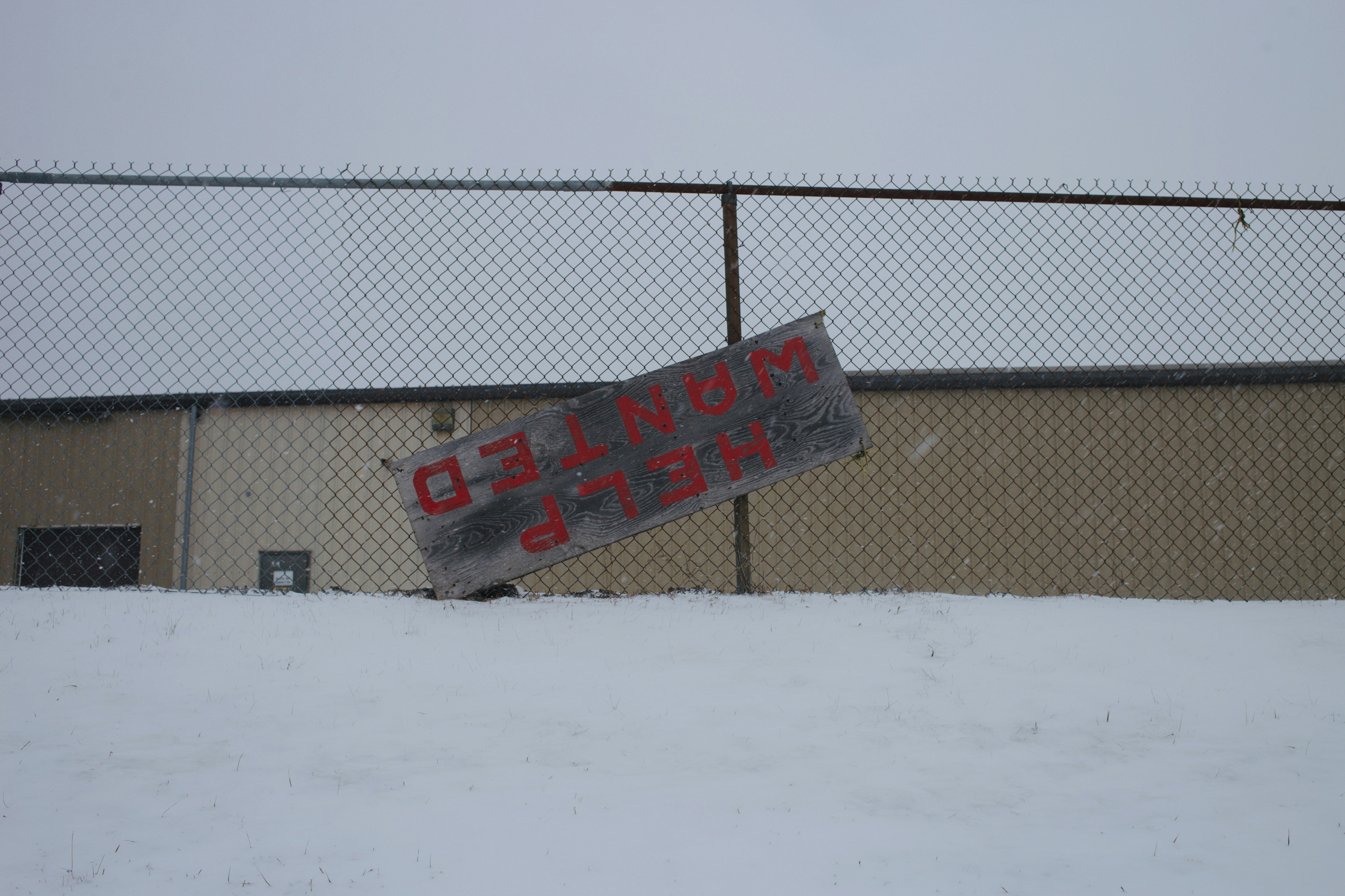 A weathered sign reads help wanted in red letters.