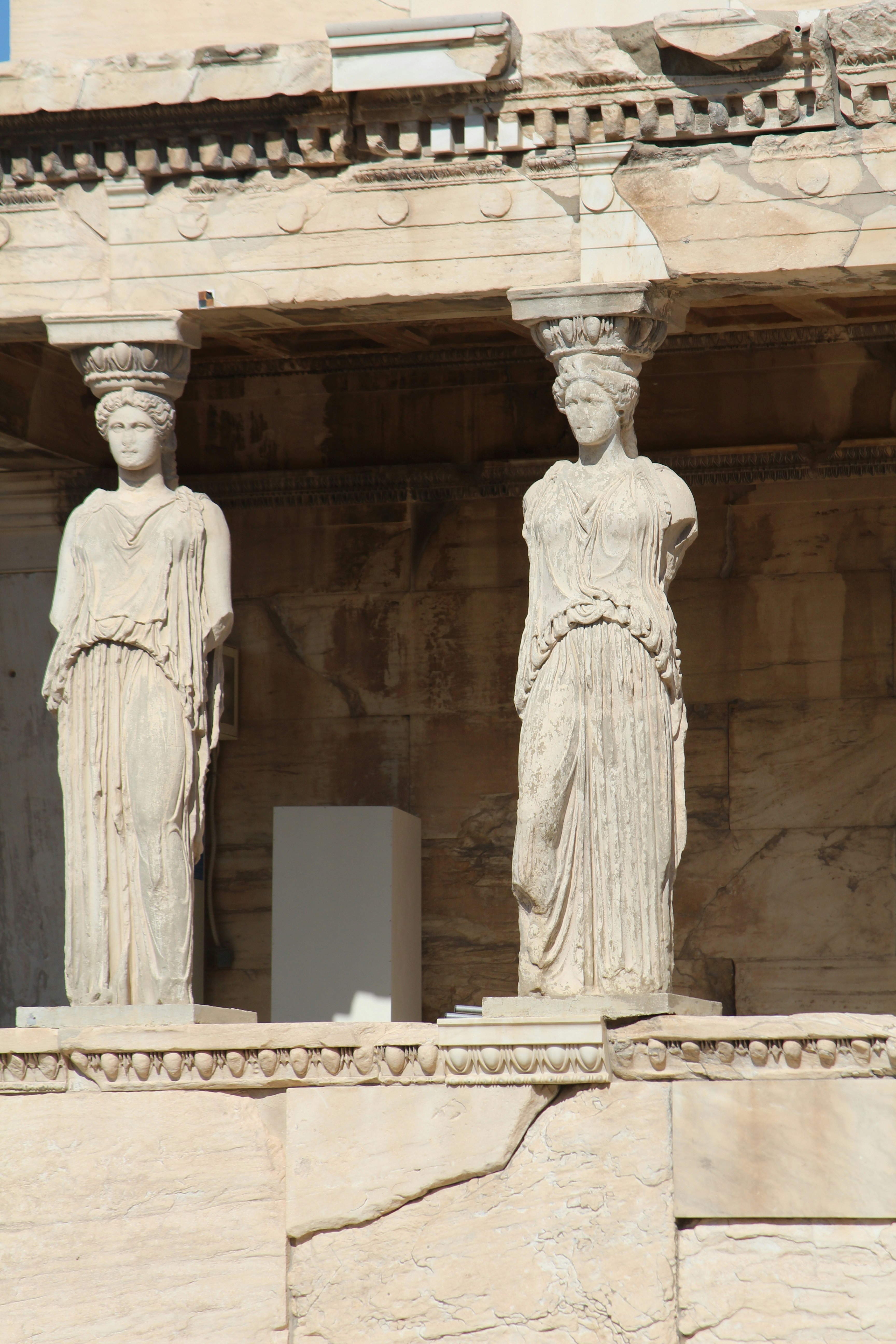 Zwei antike griechische Karyatidenstatuen, die ein Dach tragen.