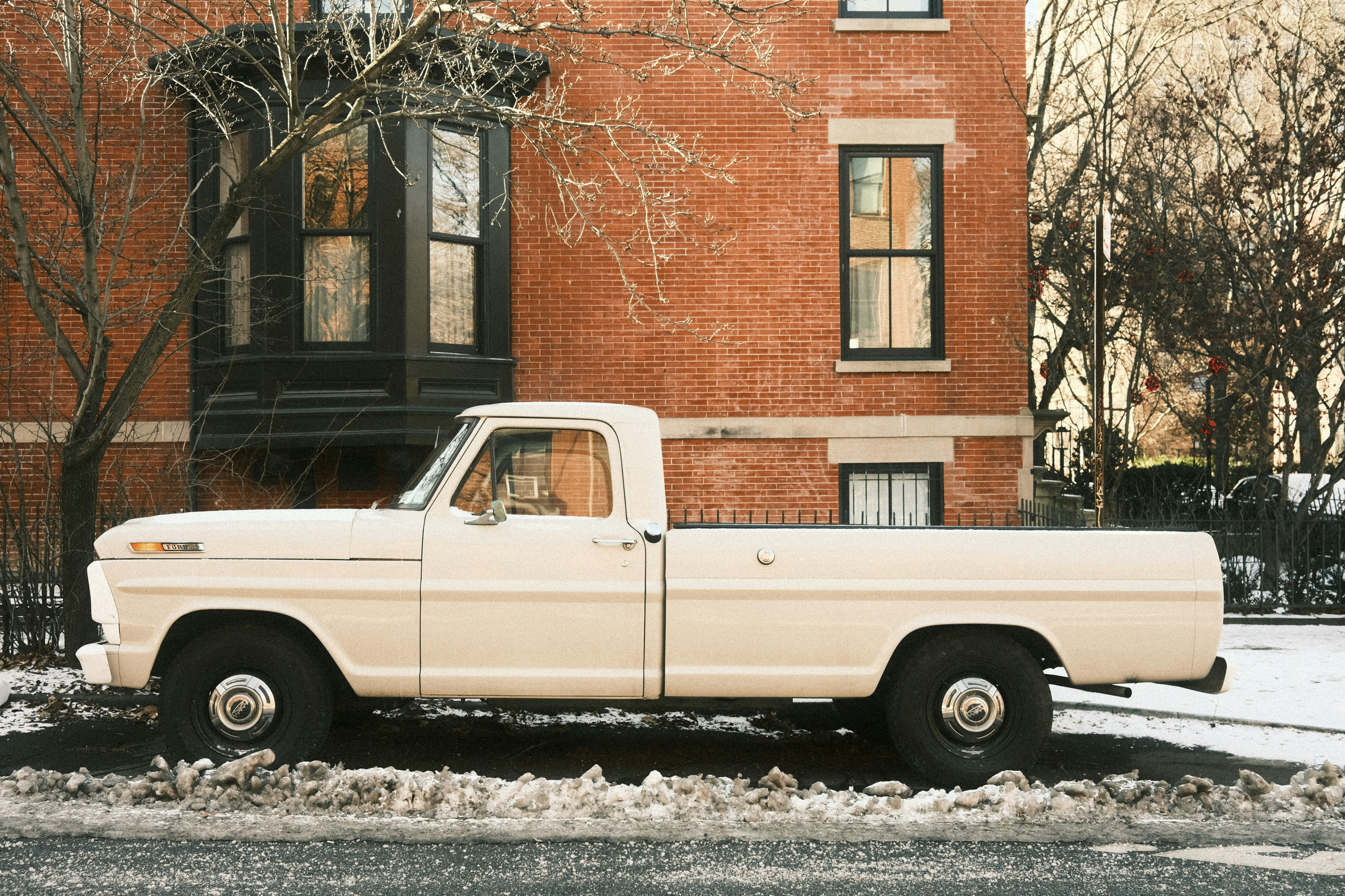 Cream colored vintage pickup truck parked on street.