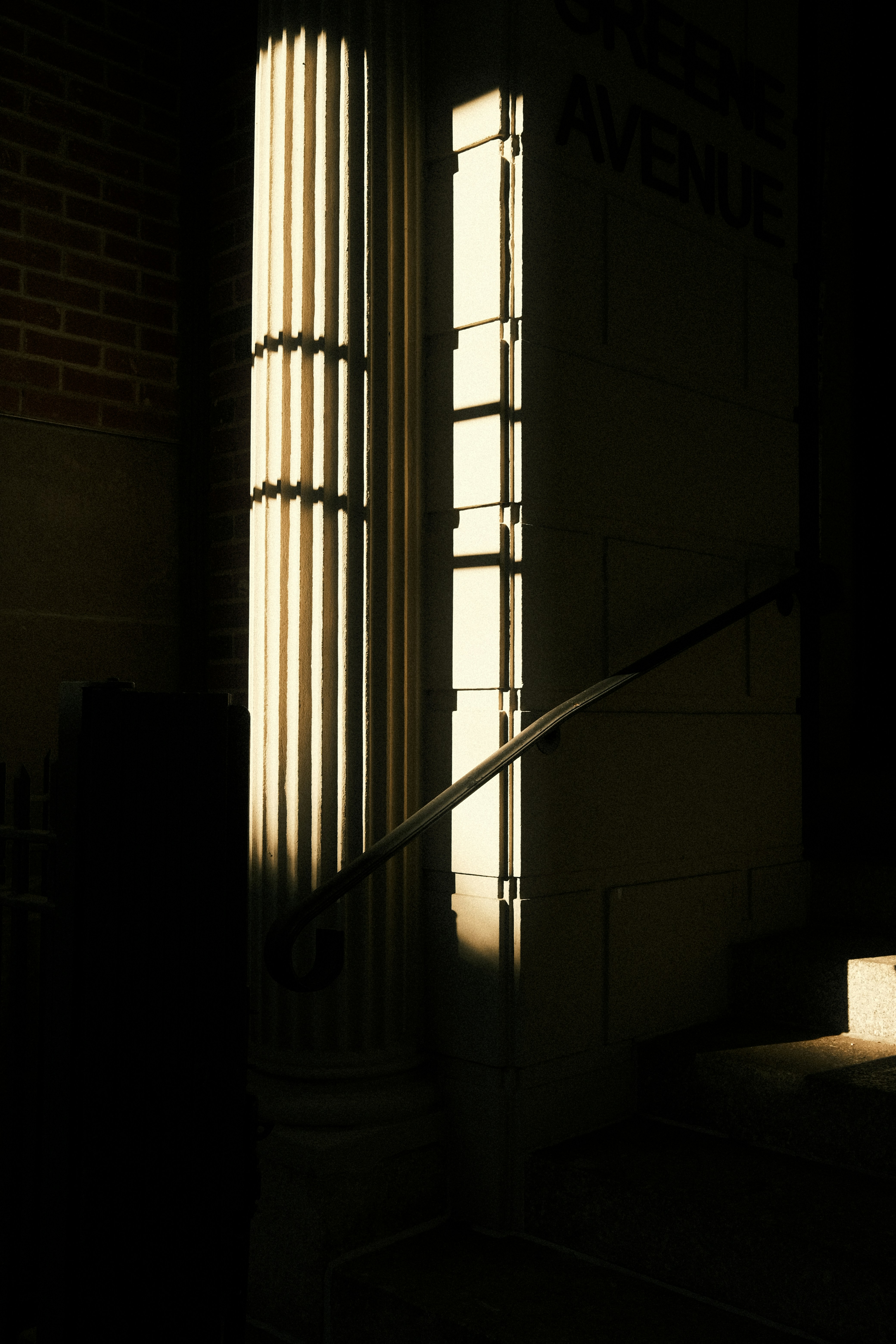 Tall illuminated columns beside a brick wall.