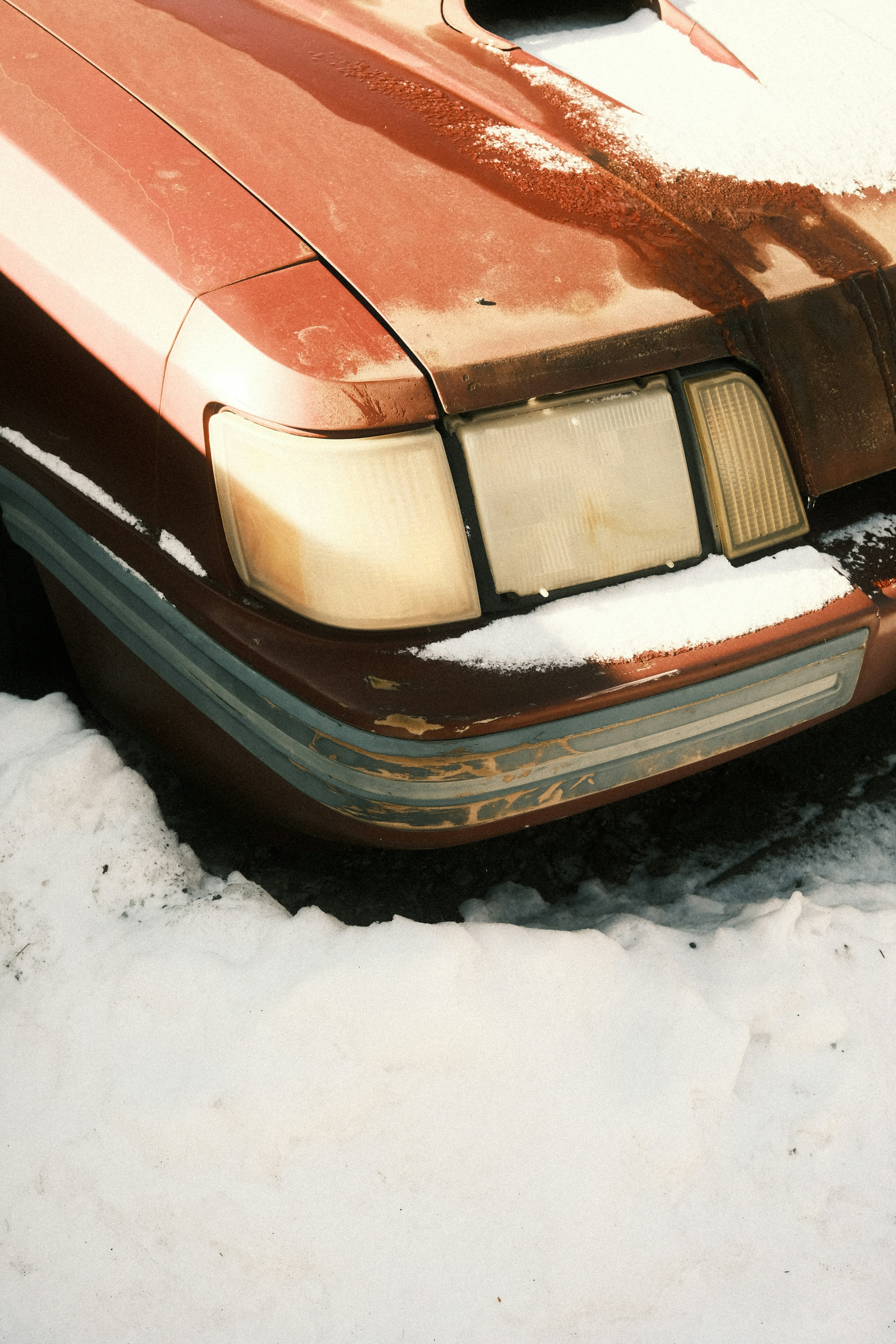Close-up of a rusty car covered in snow.