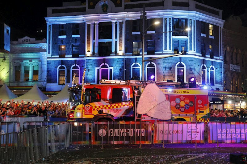 Fire trucks at a nighttime event with illuminated building