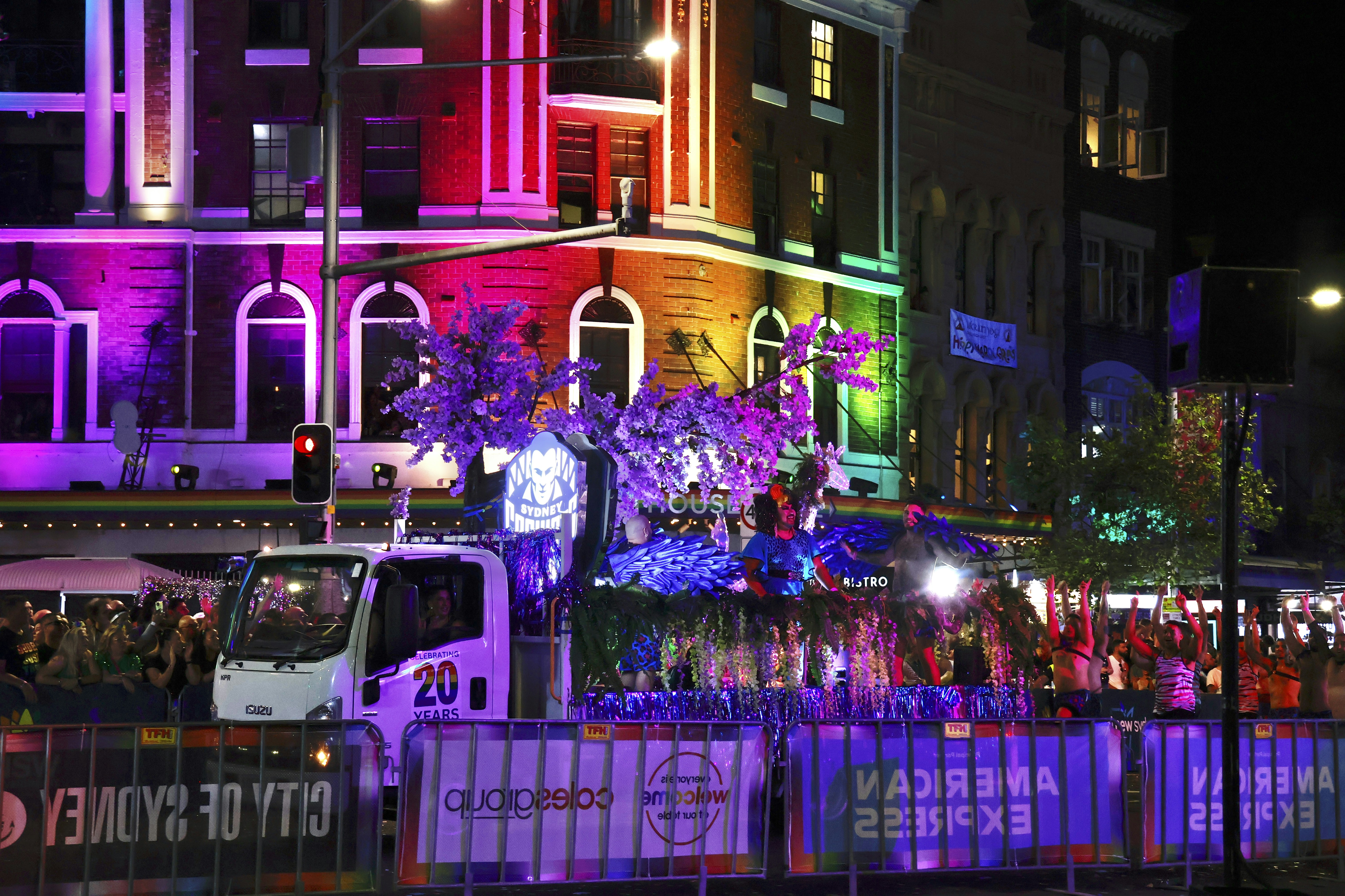 A colorful parade float at night with buildings illuminated.