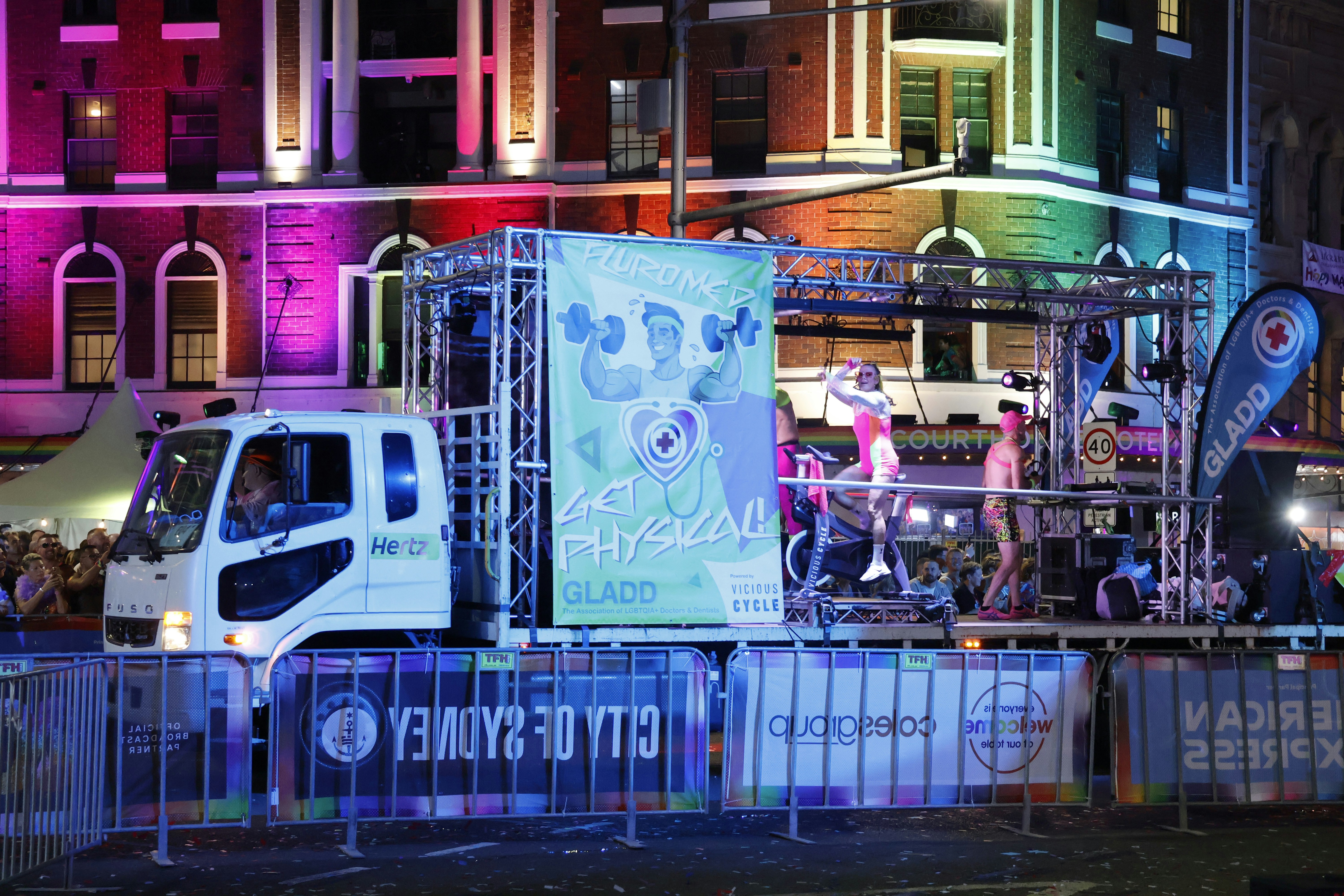 Parade float with performers and colorful building lights