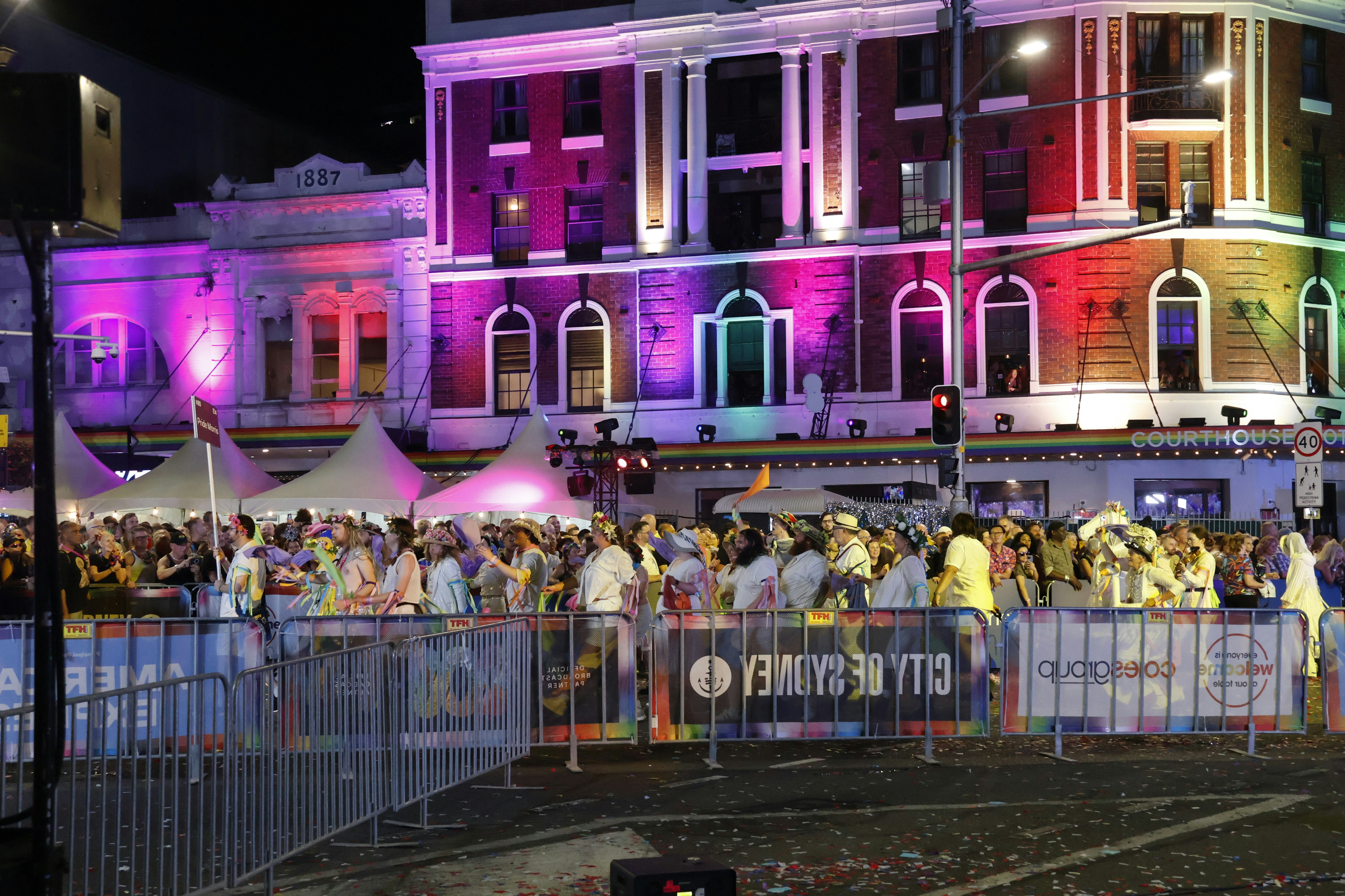 Crowd gathered at a building illuminated with rainbow lights