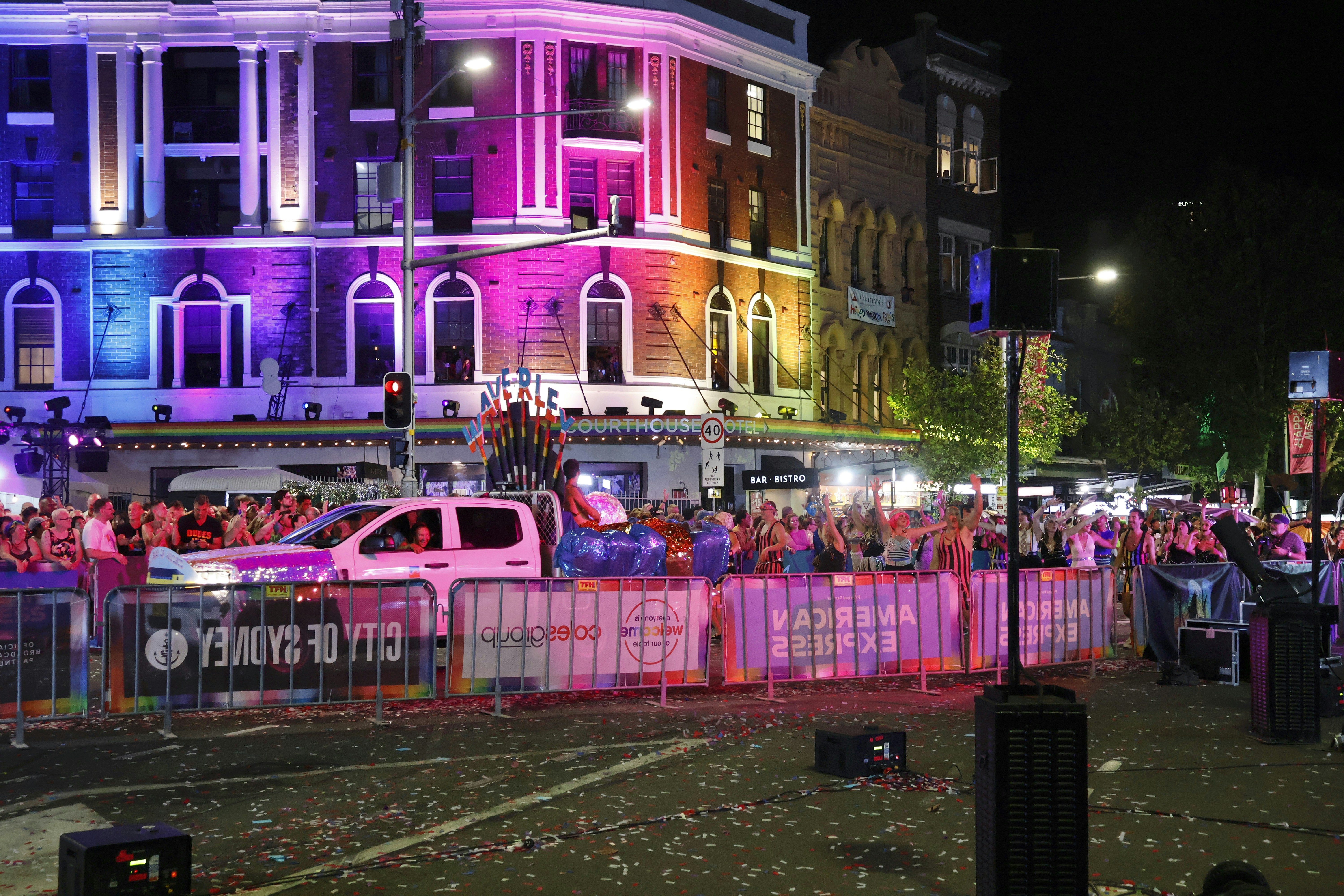 Une foule regardant un défilé avec des bâtiments éclairés par des lumières colorées